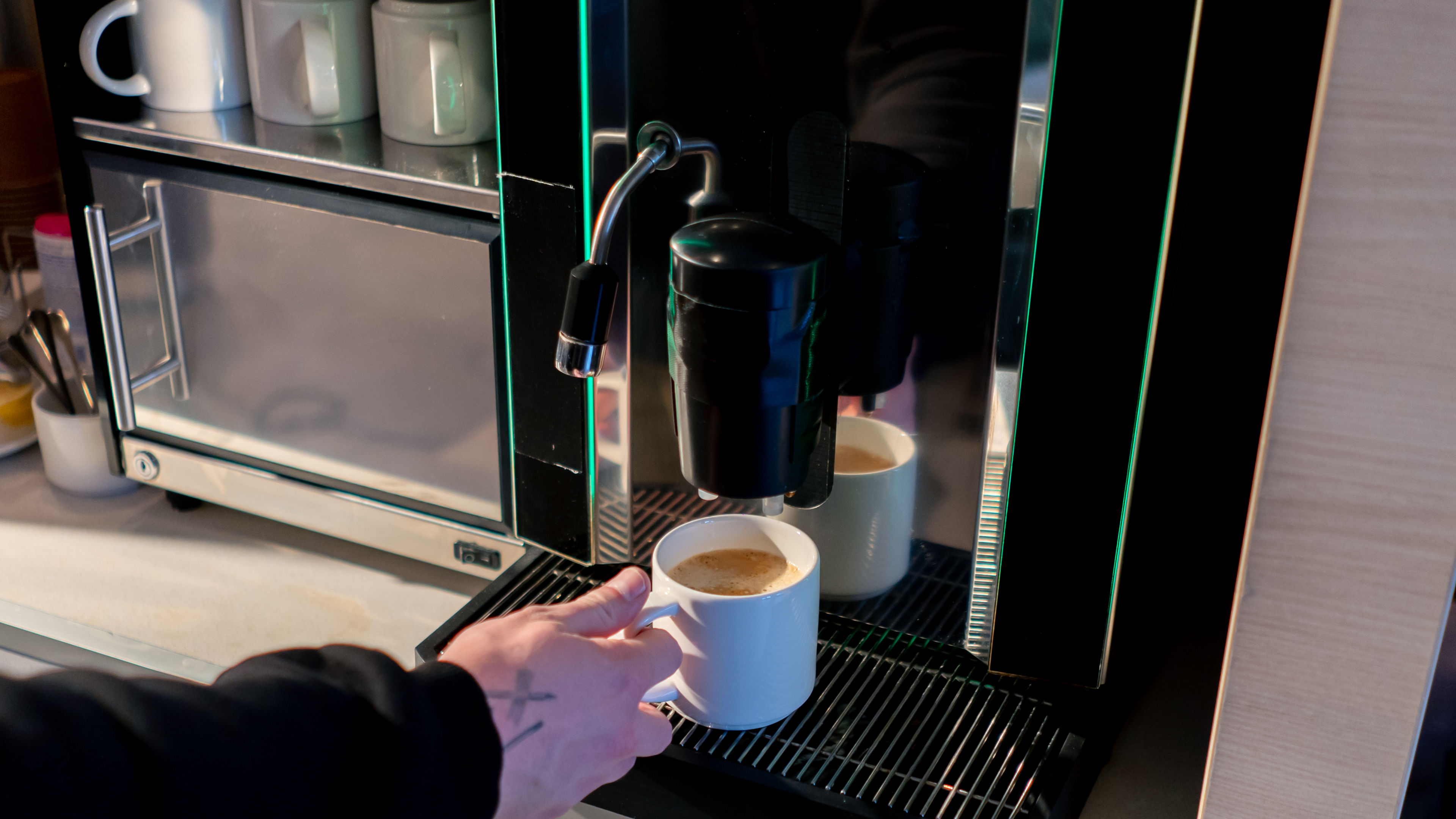 The rich aroma of coffee fills the air as an automatic coffee machine brews a fresh, fragrant cup 