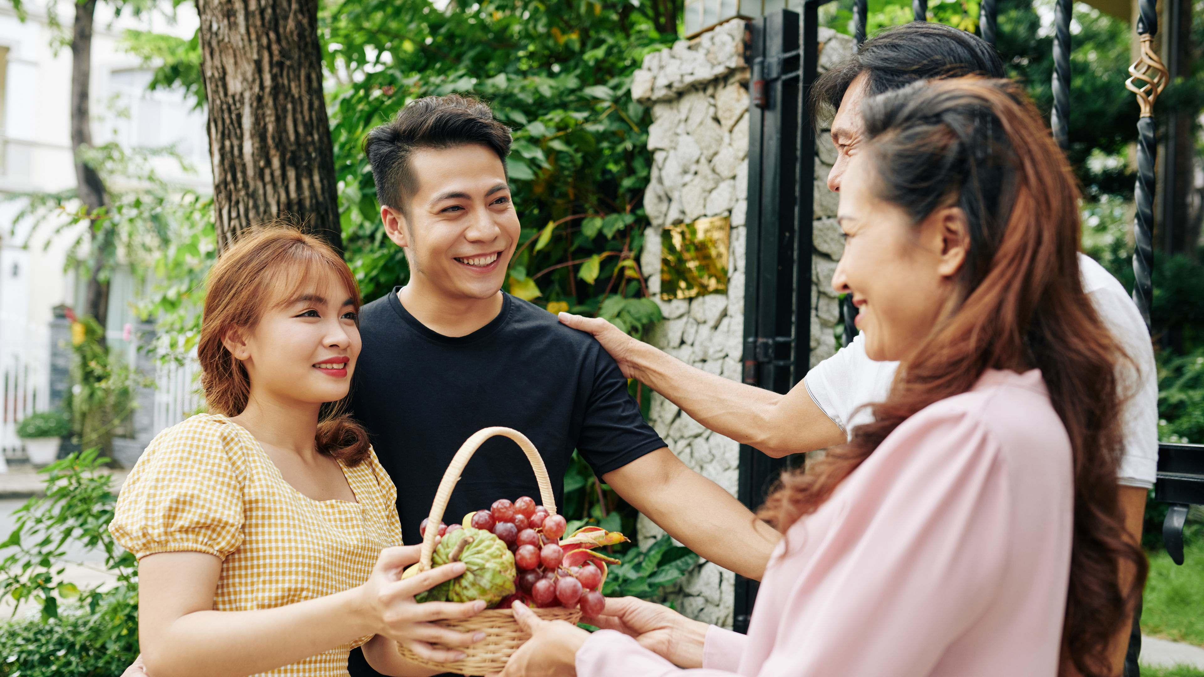 A couple gifts a basket of fruits to their parents as a gesture of respect and love 