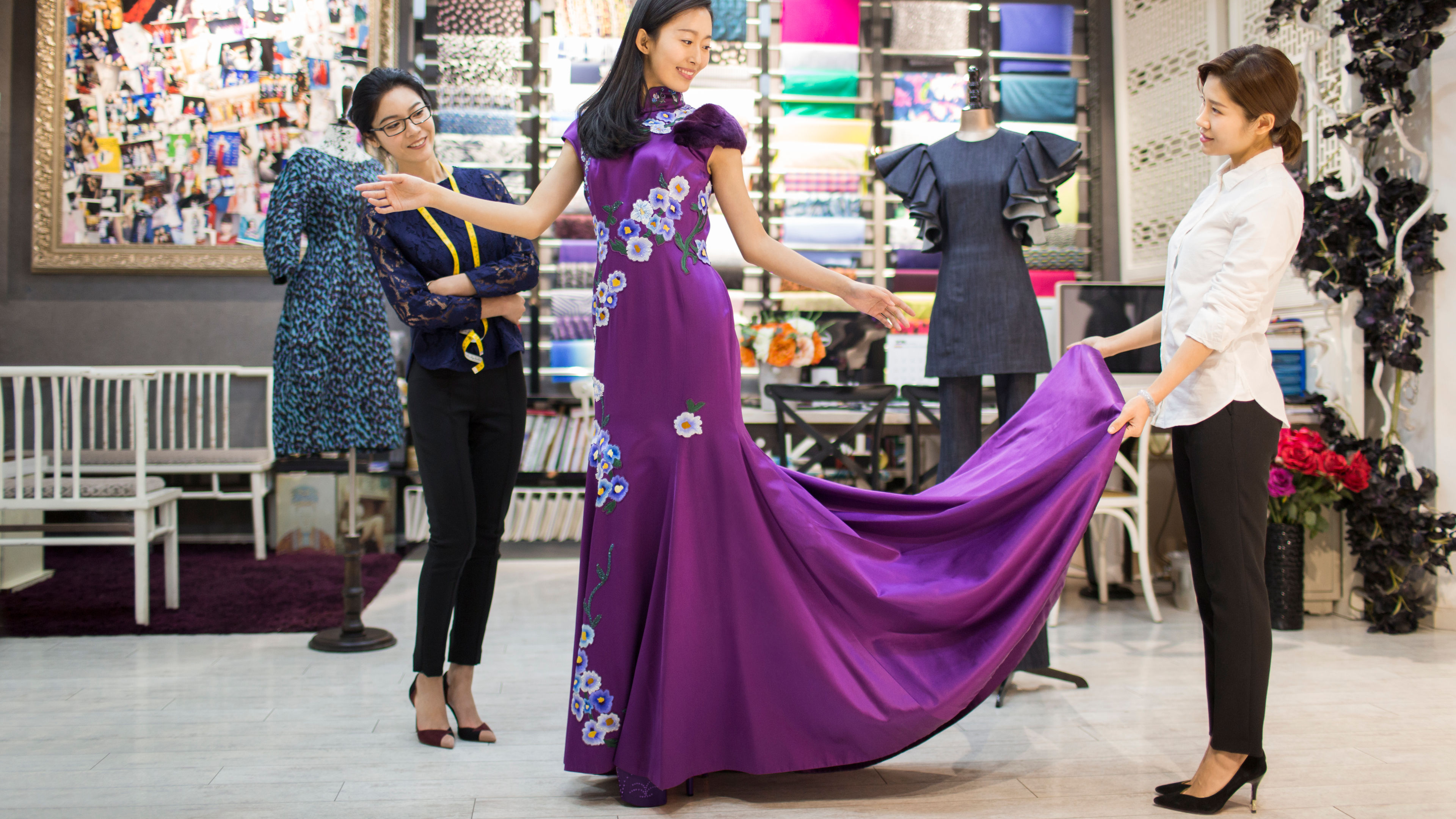 Fashion designers examining dress on customer in store 