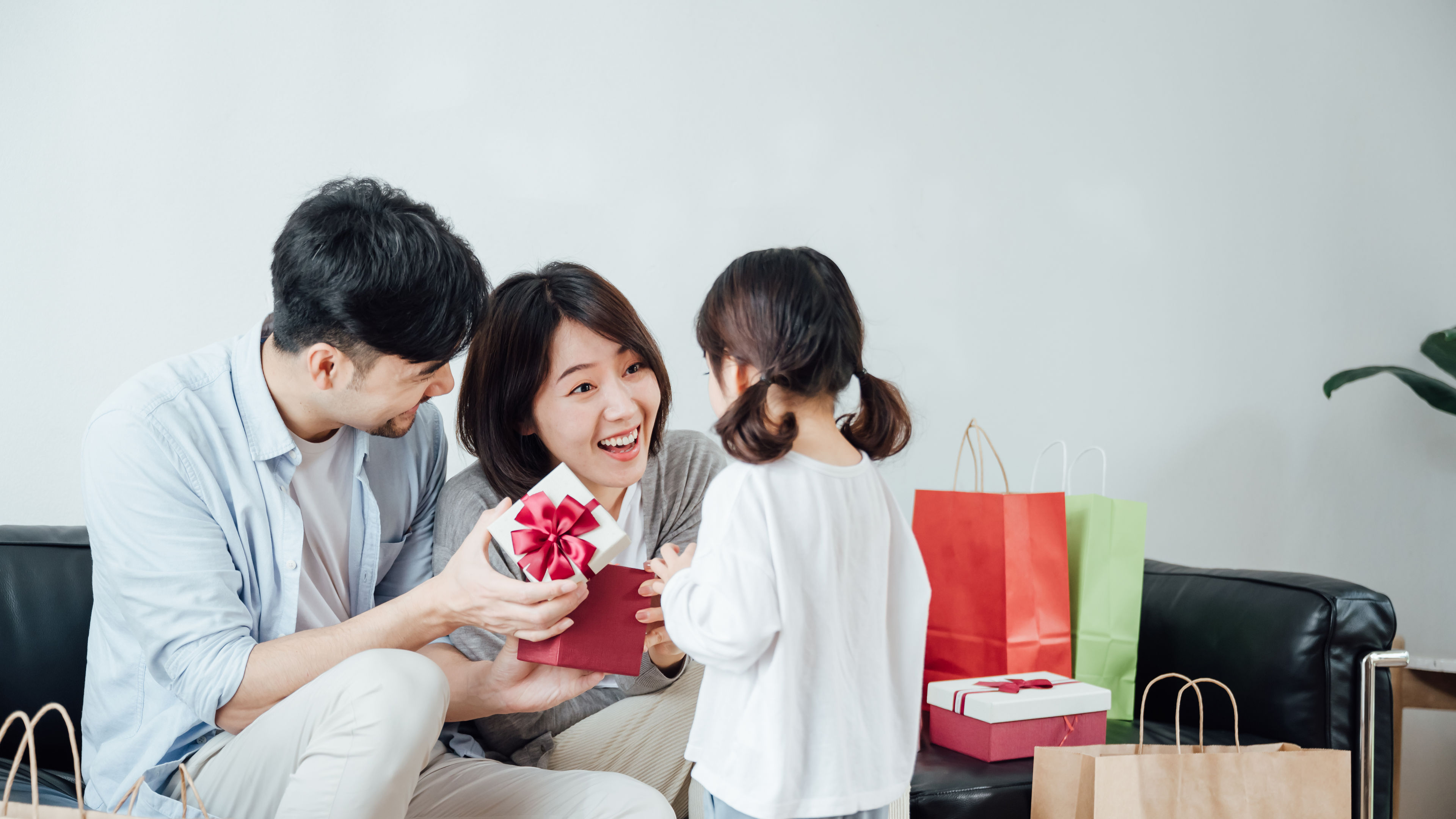 Little girl giving her parents surprising gift on festival day 