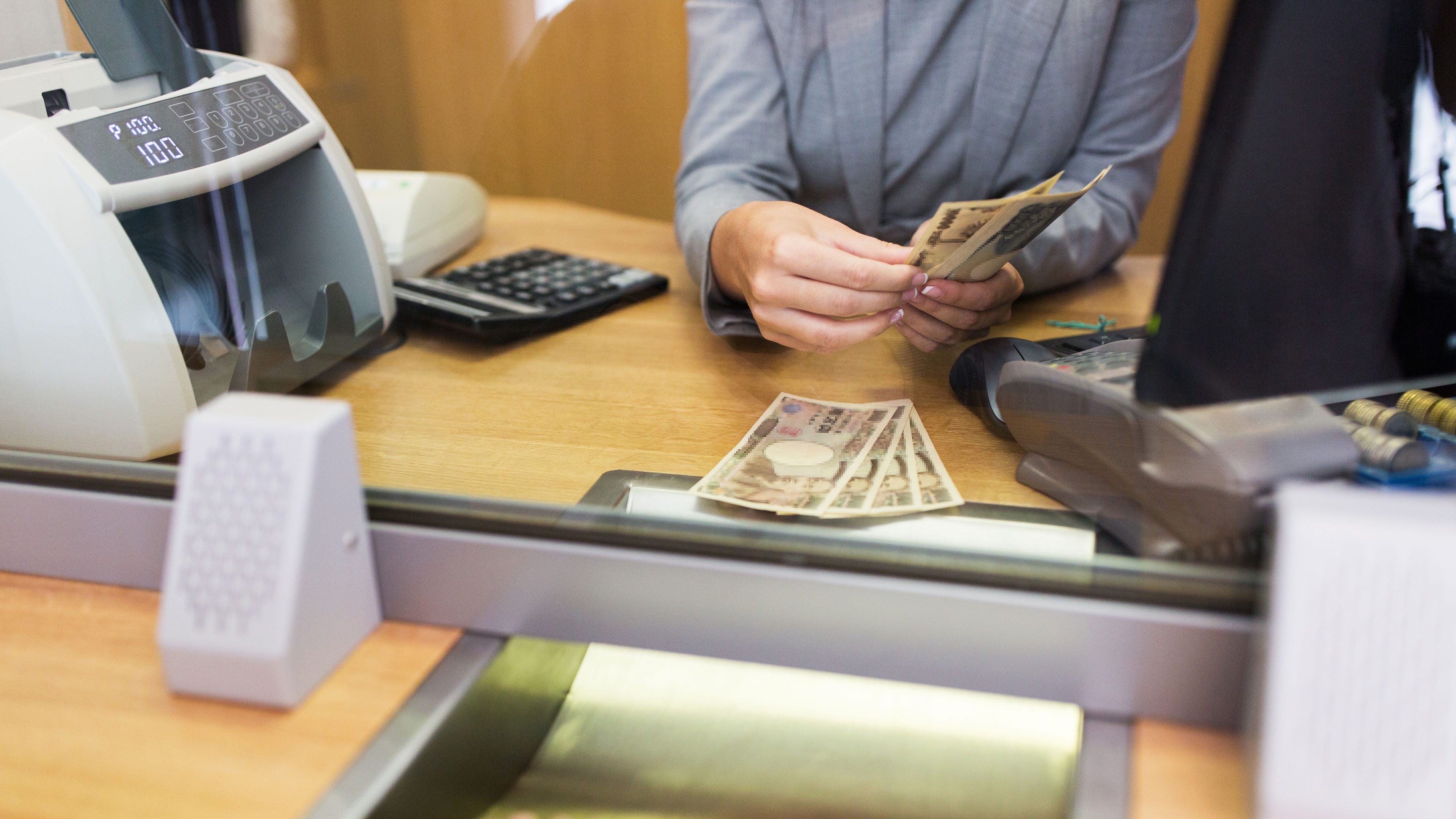 People, banking, and financial transactions concept – a clerk counting cash for a customer at a bank or currency exchange office. 