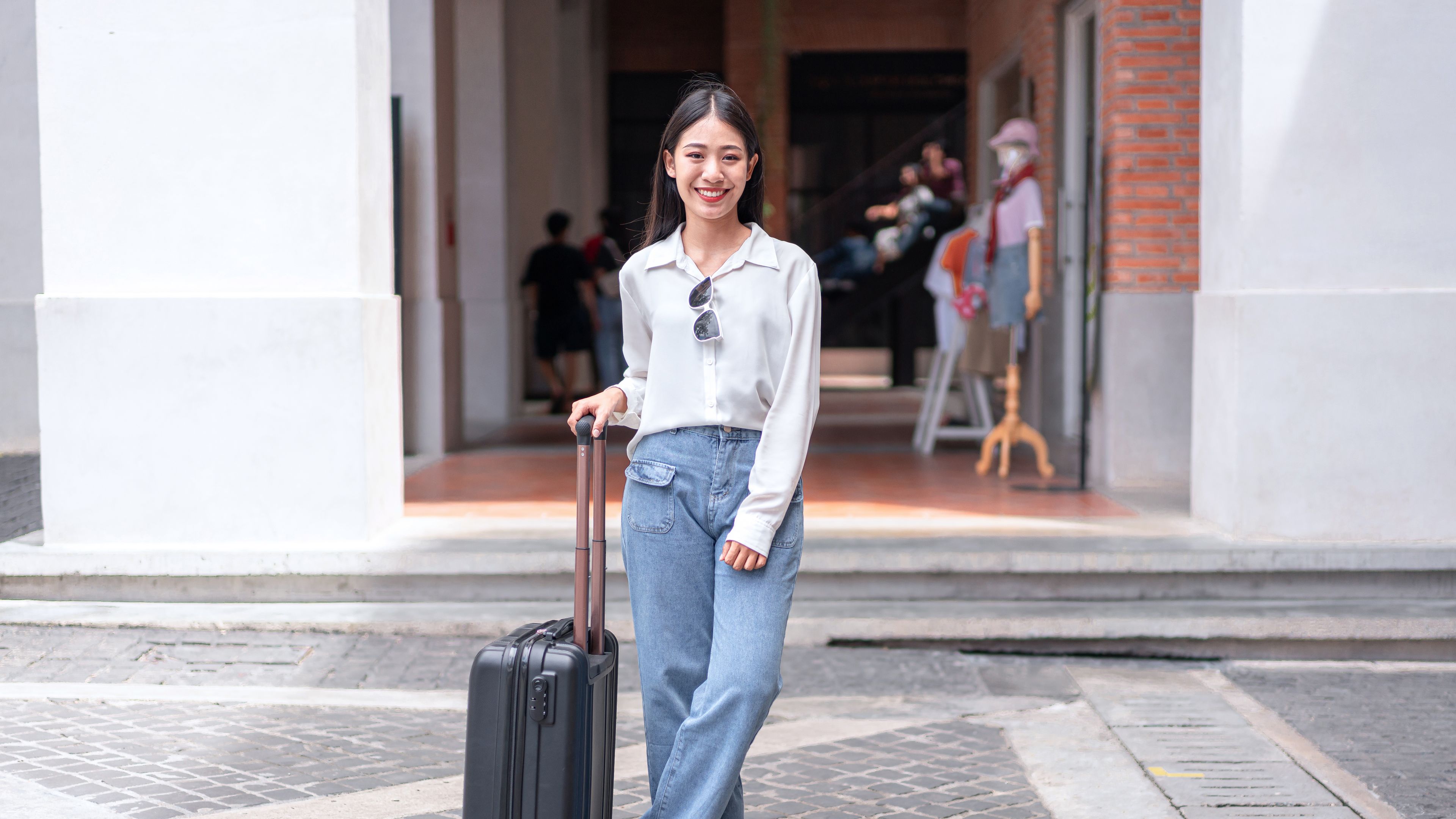 Smiling woman traveller dragging black suitcase 