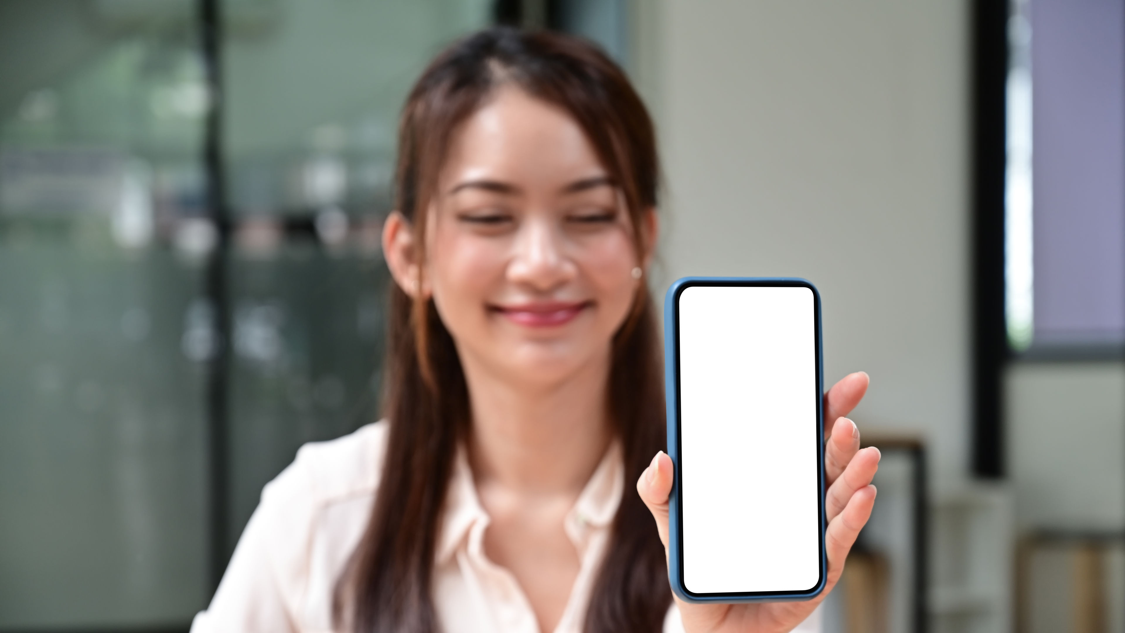 Smiling young woman showing mock up smart phone