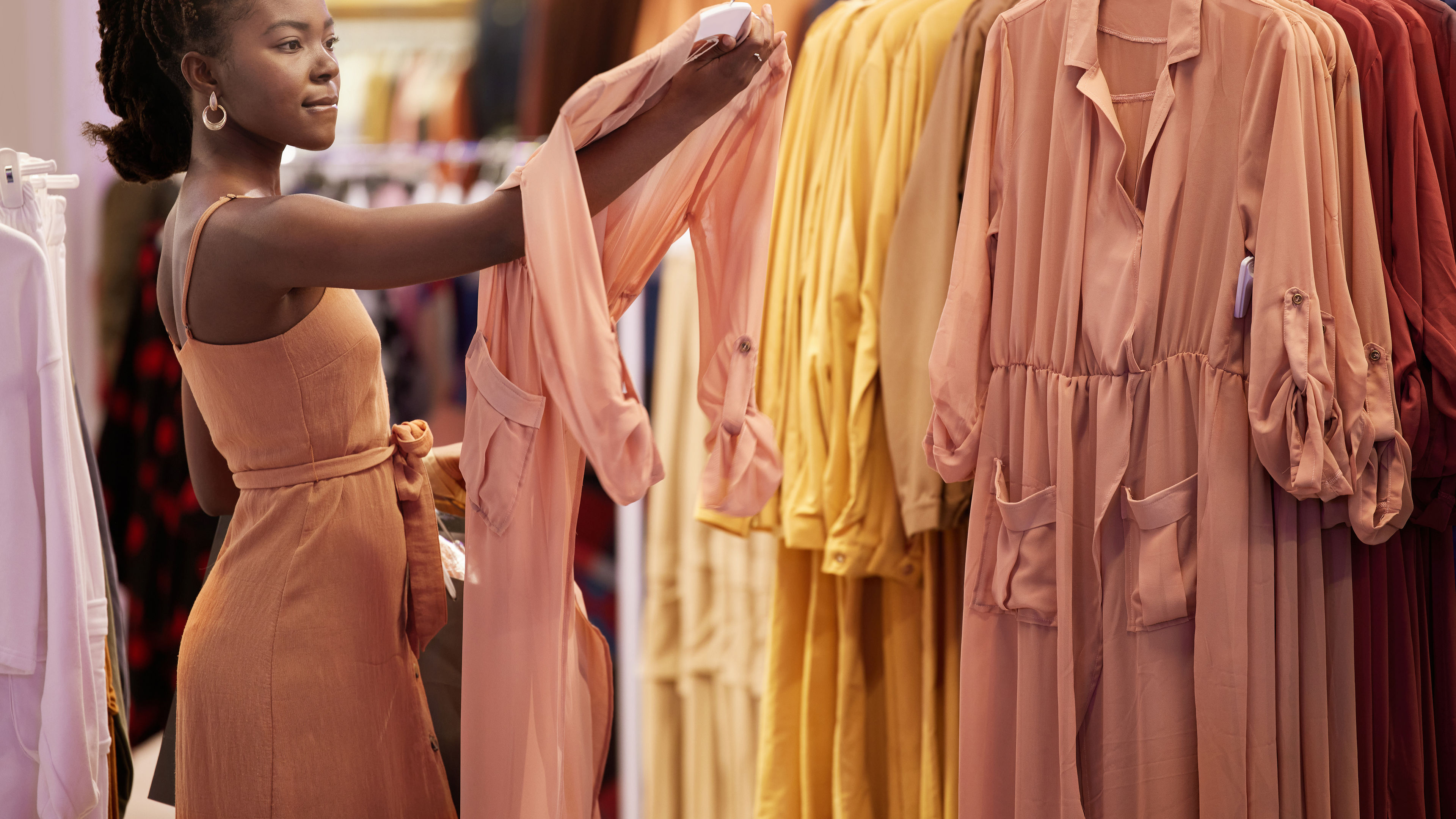 A beautifully captured scene of a woman trying on a stunning peach-colored dress in an upscale boutique’s fitting room.