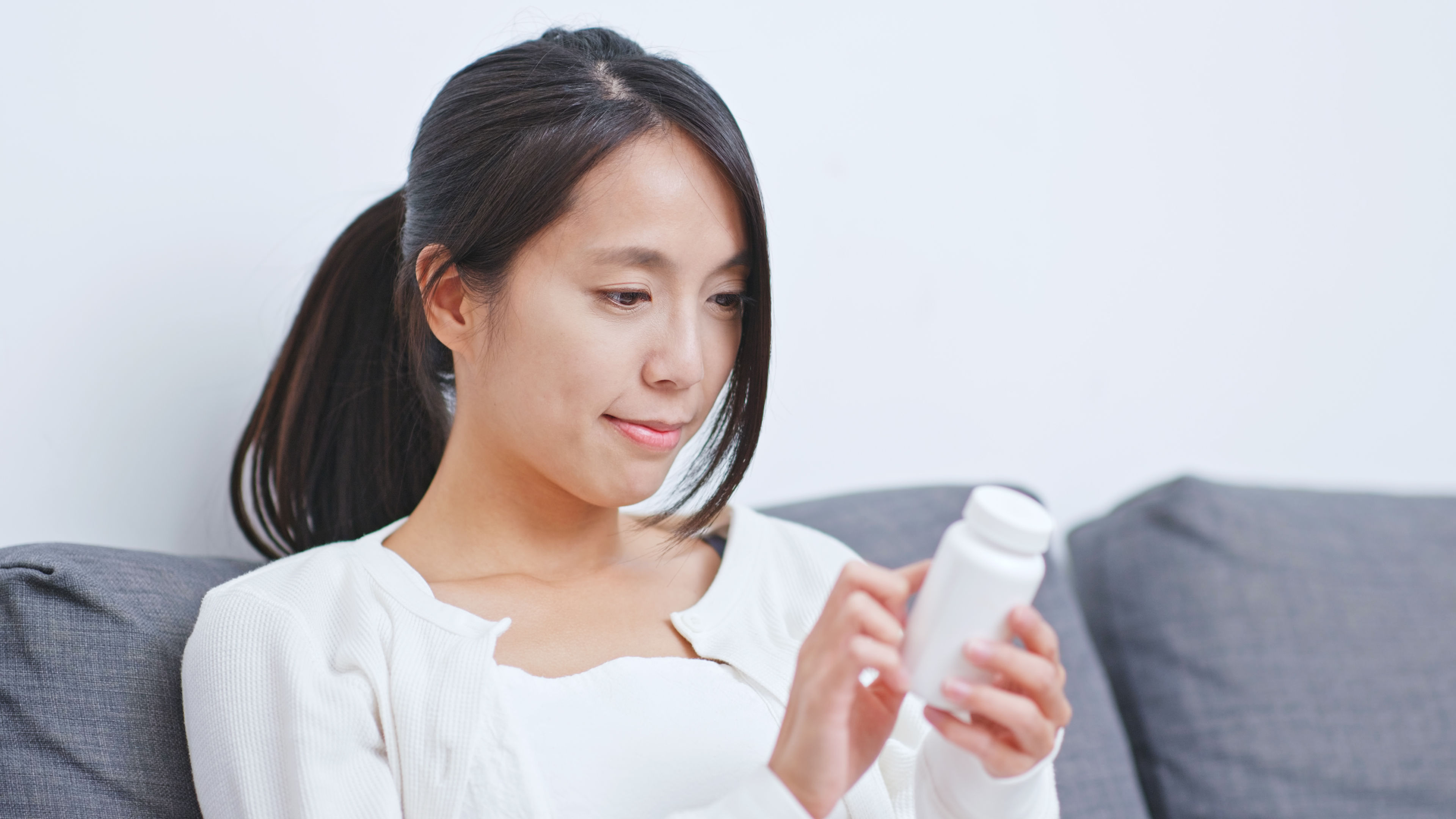 A young woman looking at a bottle for ingredients 