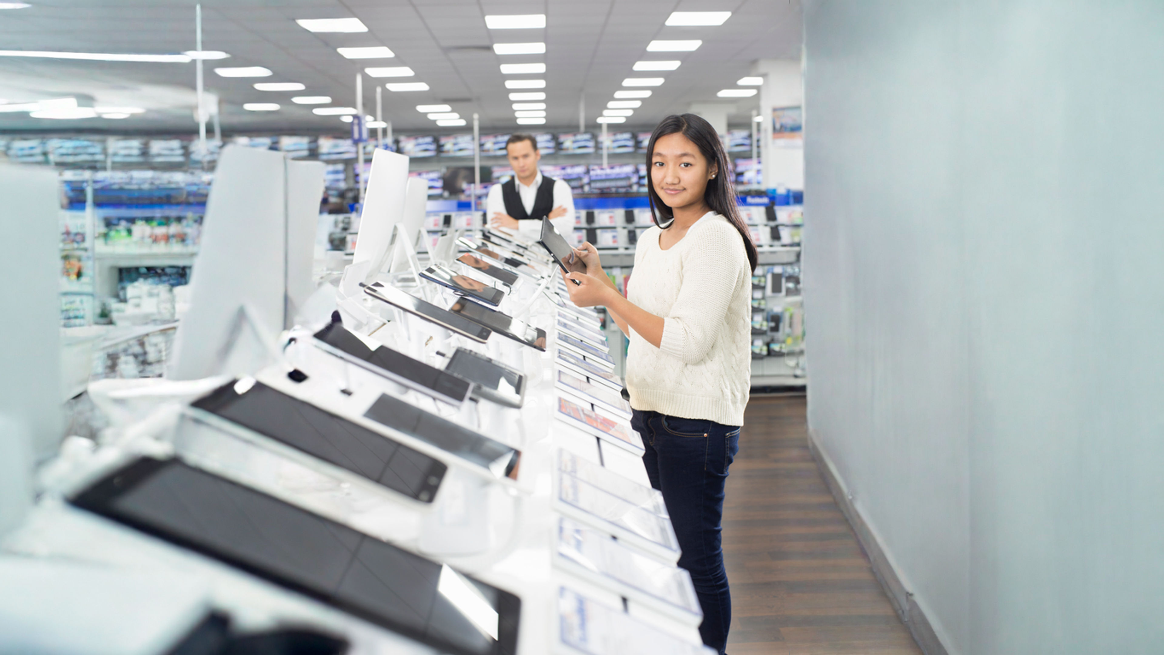 Portrait of young female shopper browsing digital tablets in electronics store