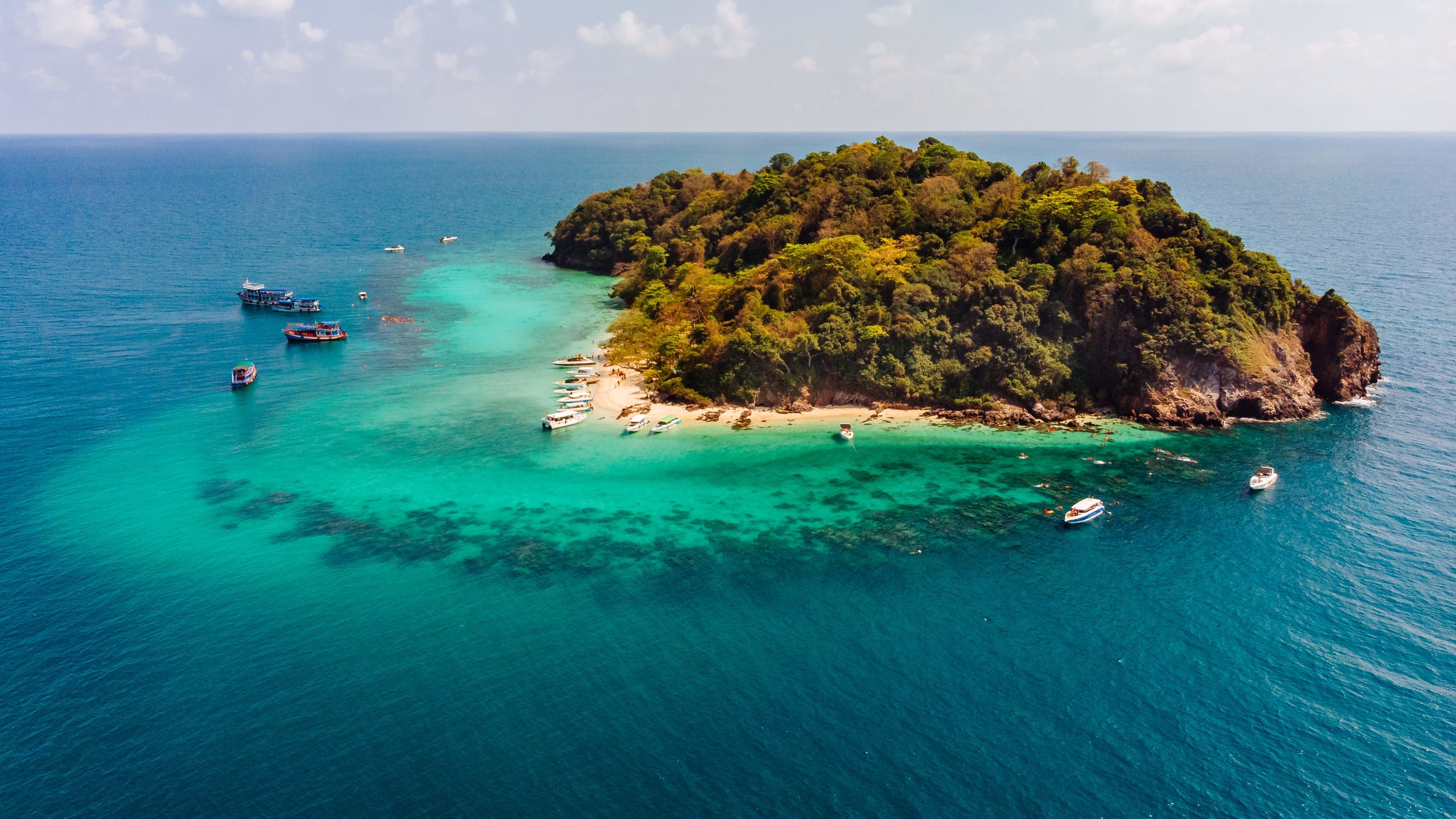 Aerial shot of a small green island in the middle of the ocean 

 