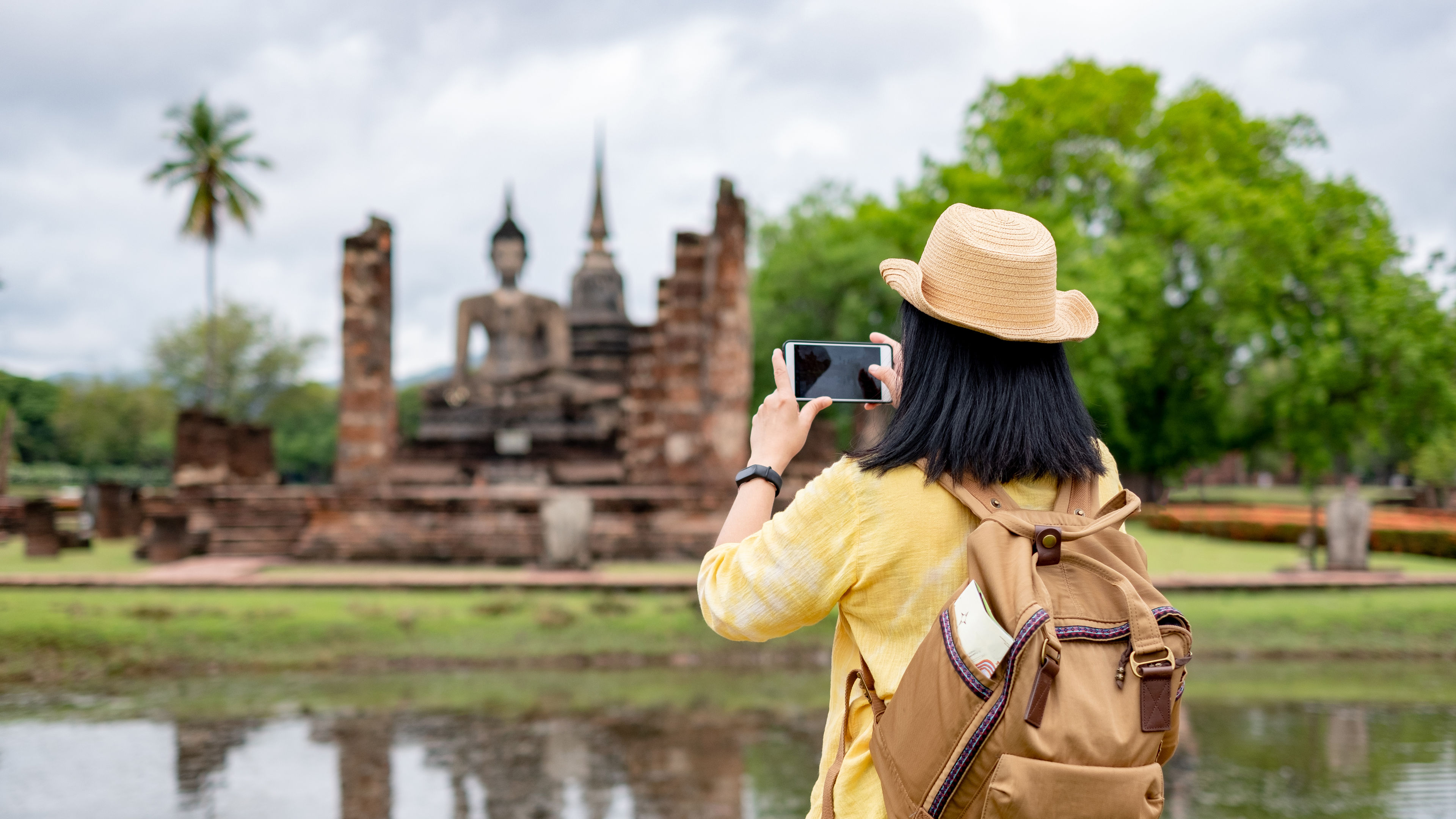 Asian tourist woman use mobile take a photo of ancient of pagoda temple thai architecture. 