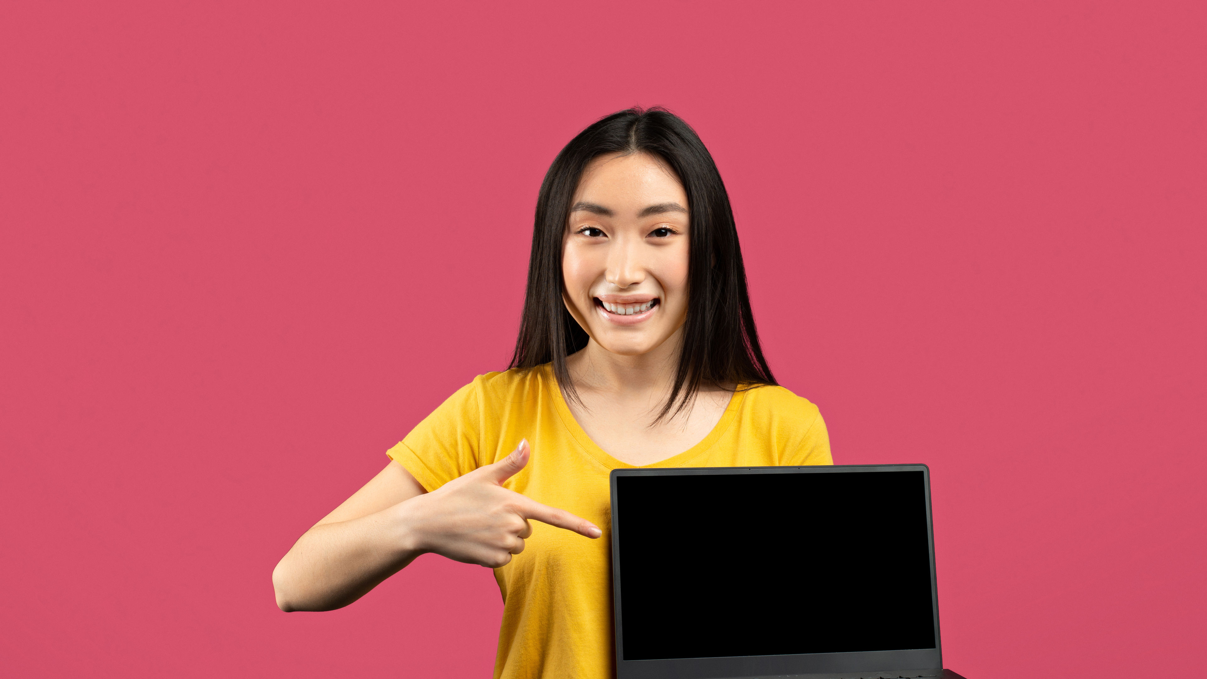 Nice online offer. Happy korean lady shopping online, holding modern laptop, pointing at computer 