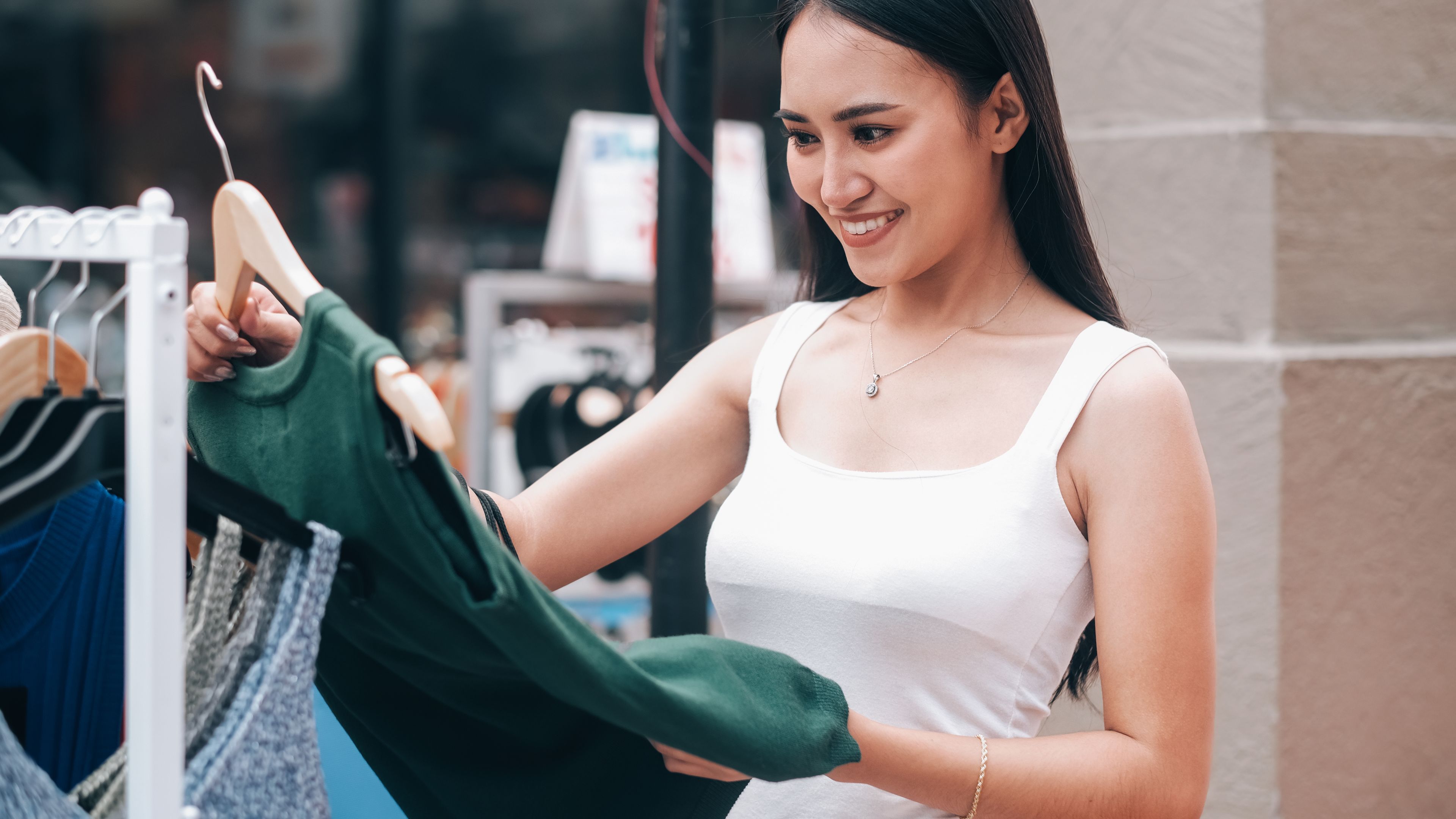 A woman holding a beautiful dress in her hand, deciding whether to try it on.