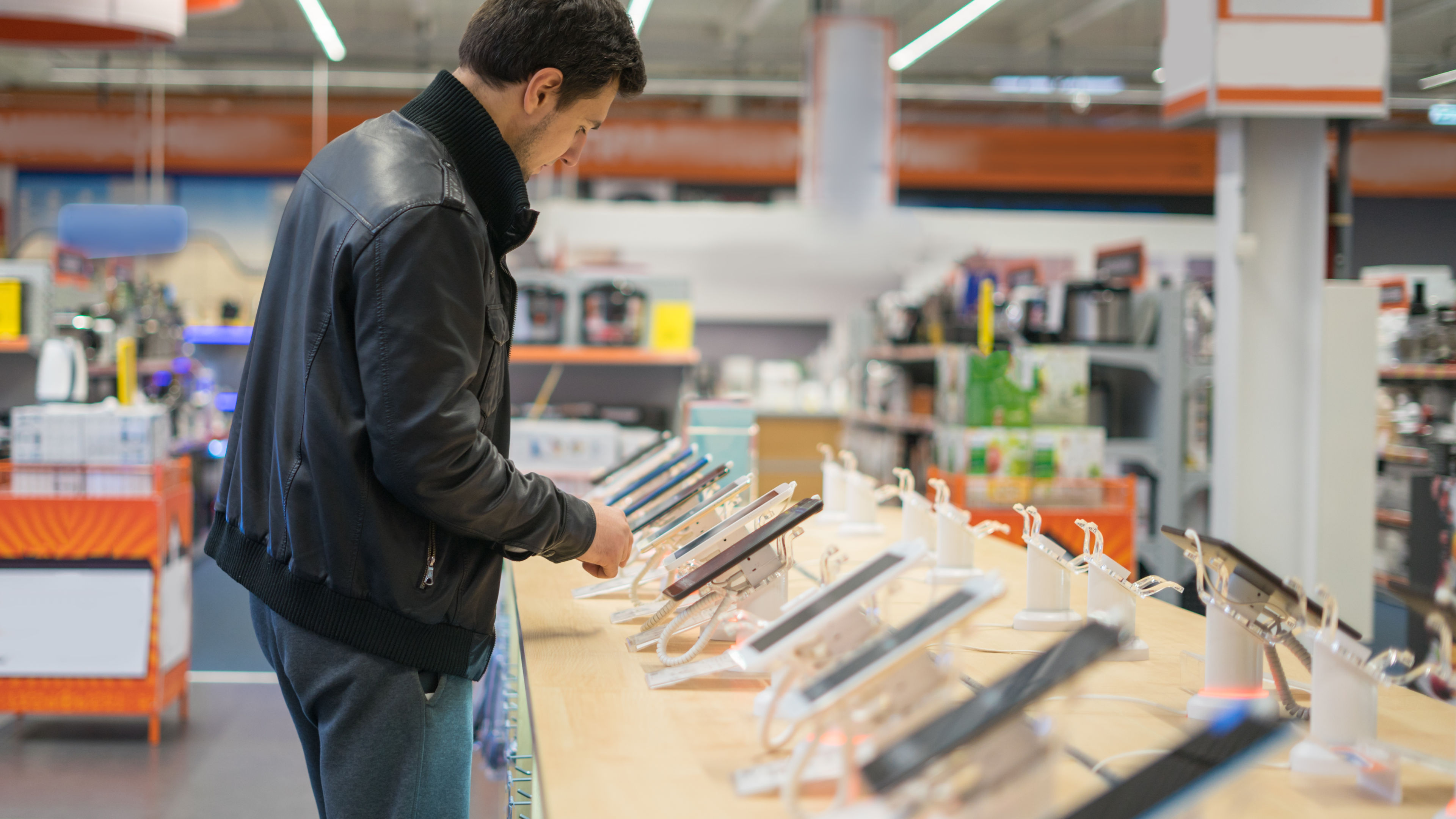 A man browsing through a variety of mobile phones on display in a mobile shop, carefully considering his options.