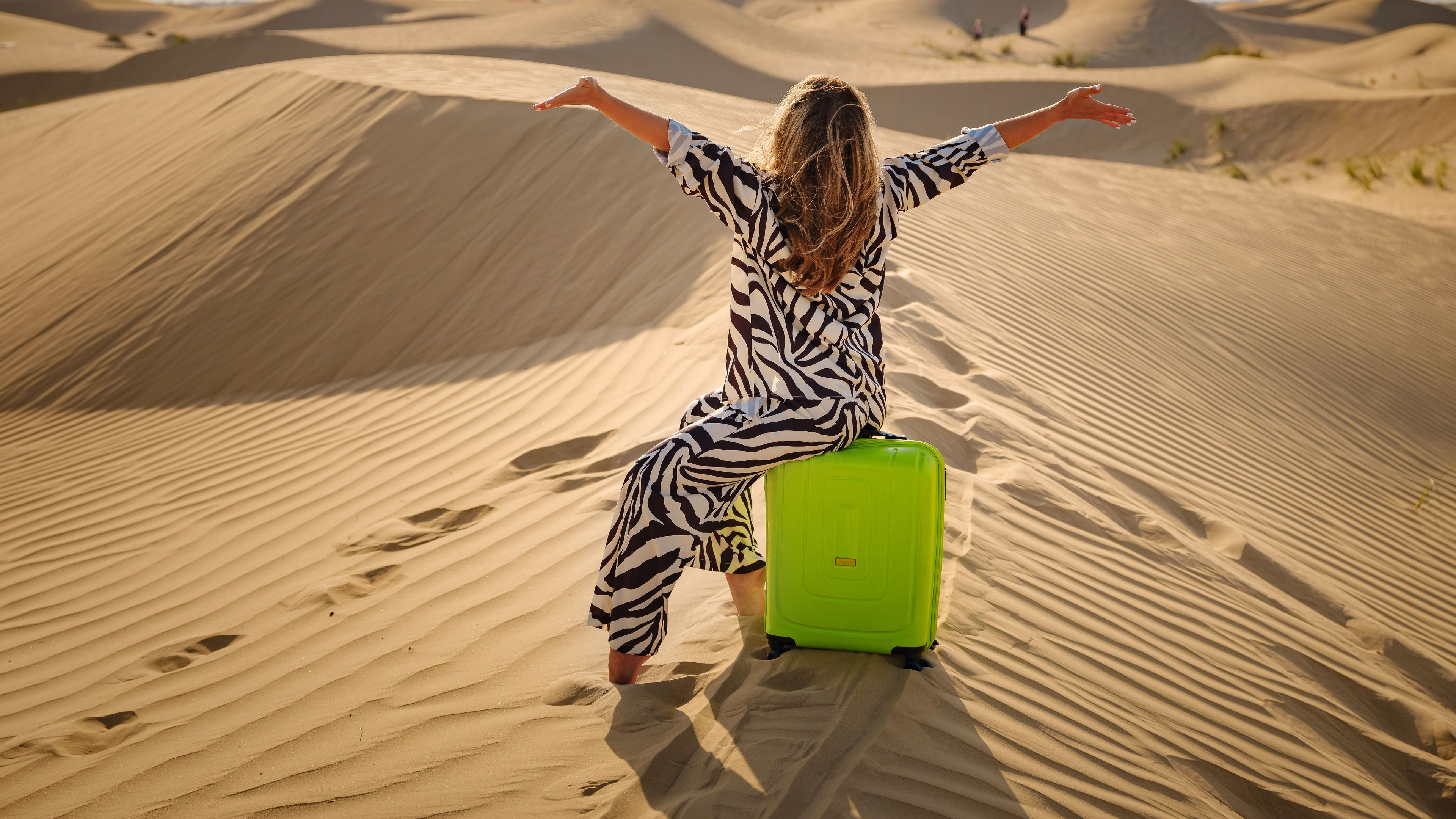 A woman sitting on a green travel bag 