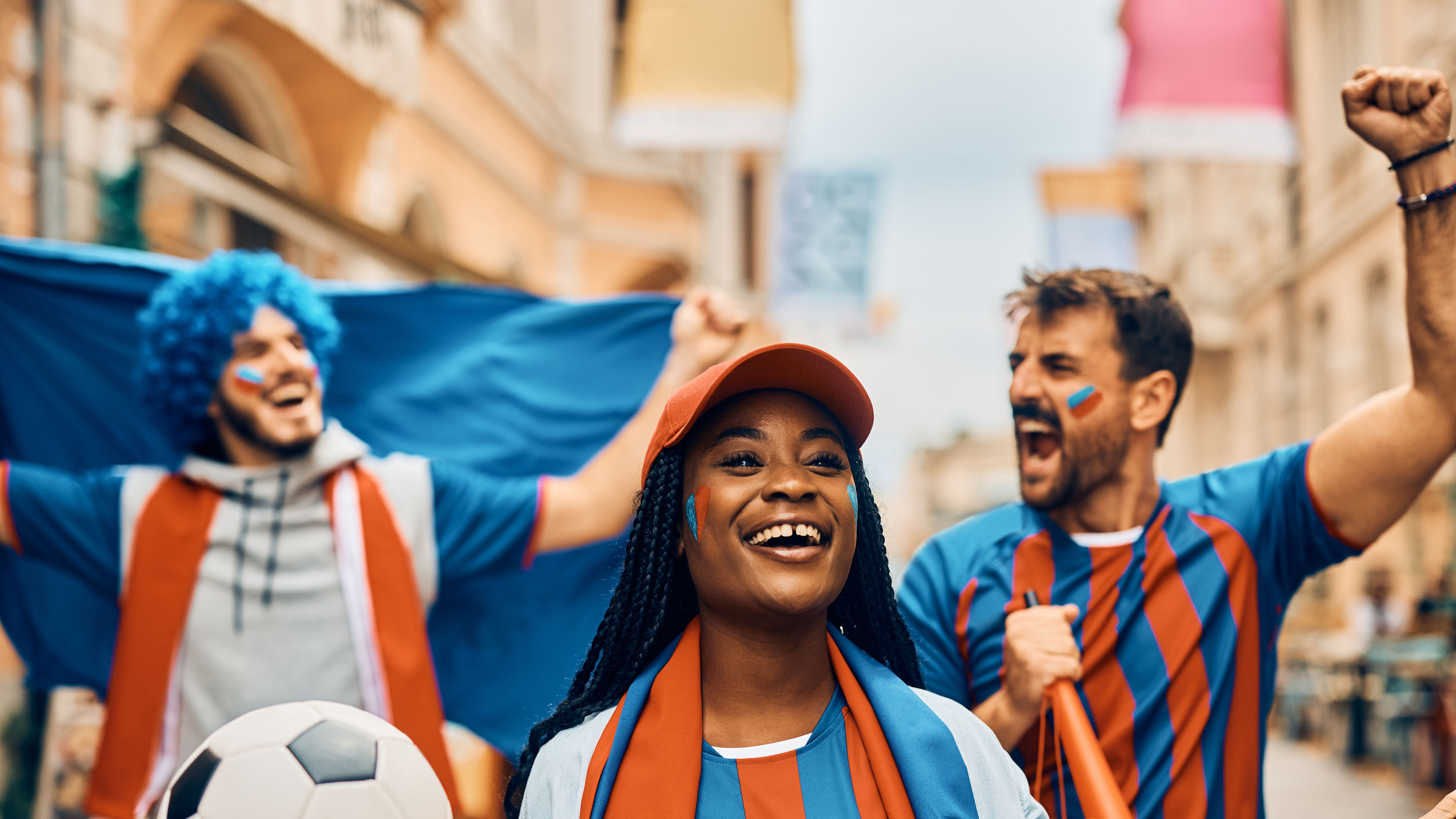 Cheerful black woman and her friends celebrating their team's victory during soccer championship. 