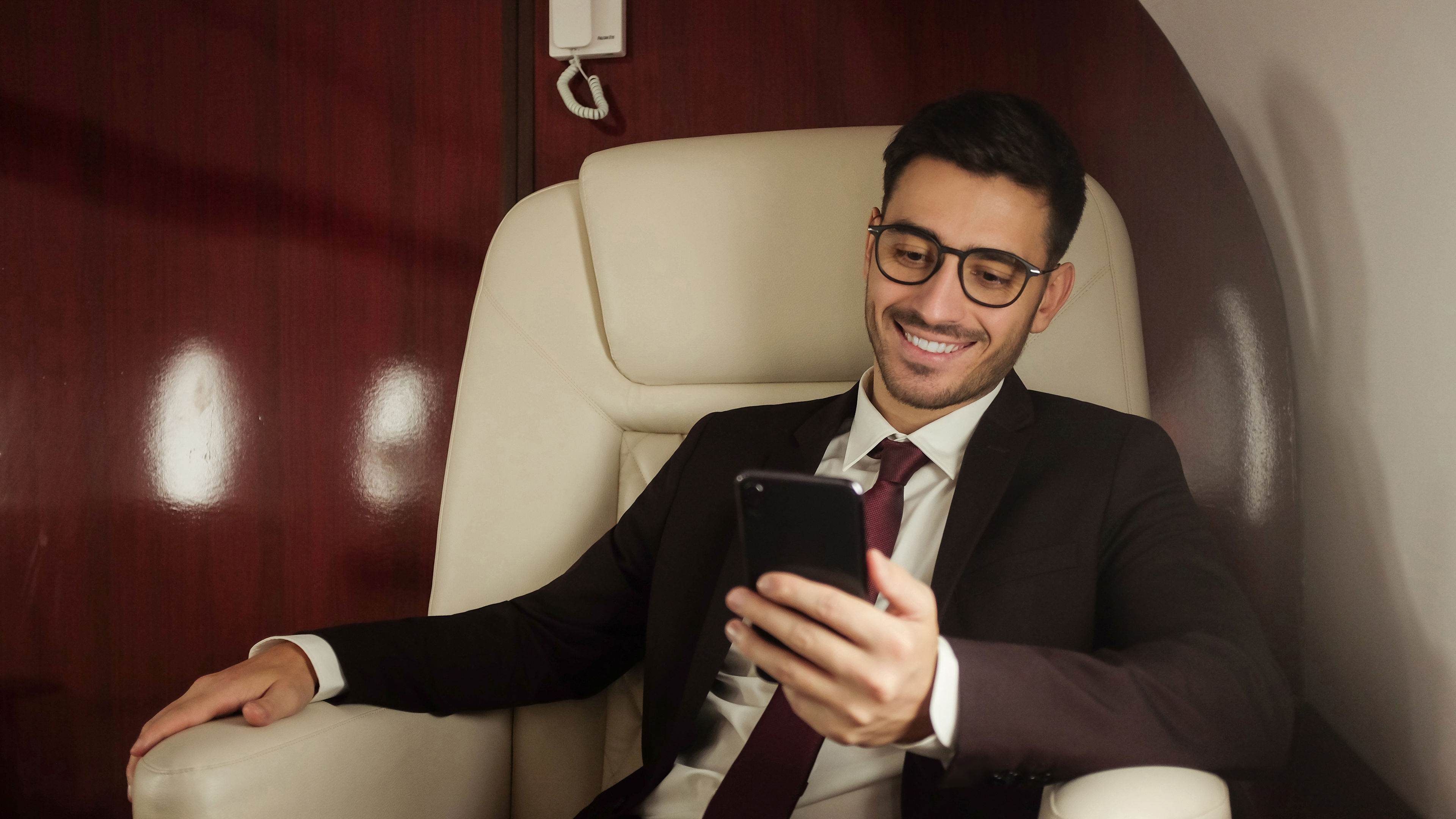 Young handsome business man travelling first class, reading text messages on smartphone 