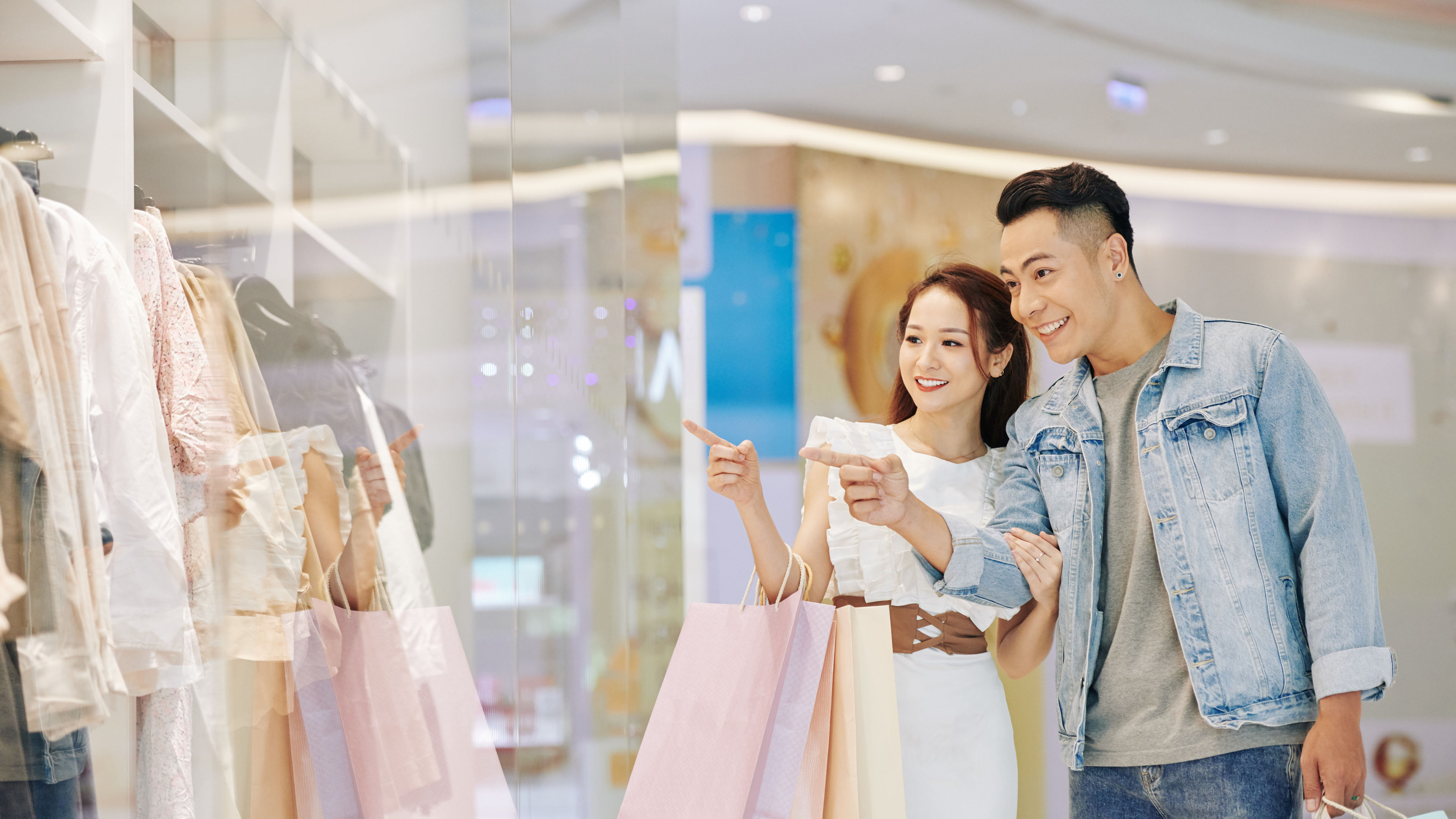 Boyfriend and girlfriend shopping together, holding bags in a retail store.