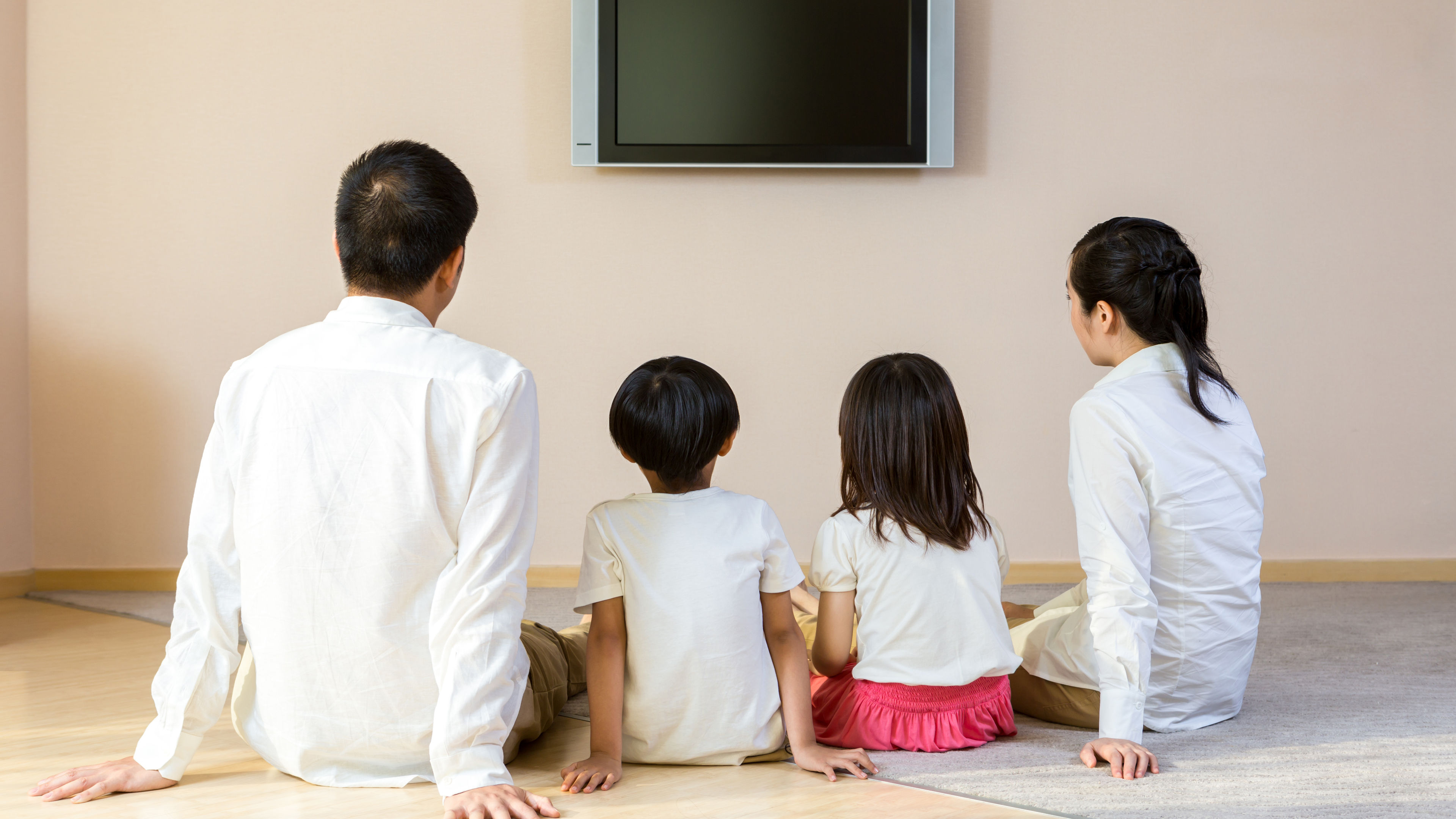 A happy family gathered around the TV, enjoying their time.