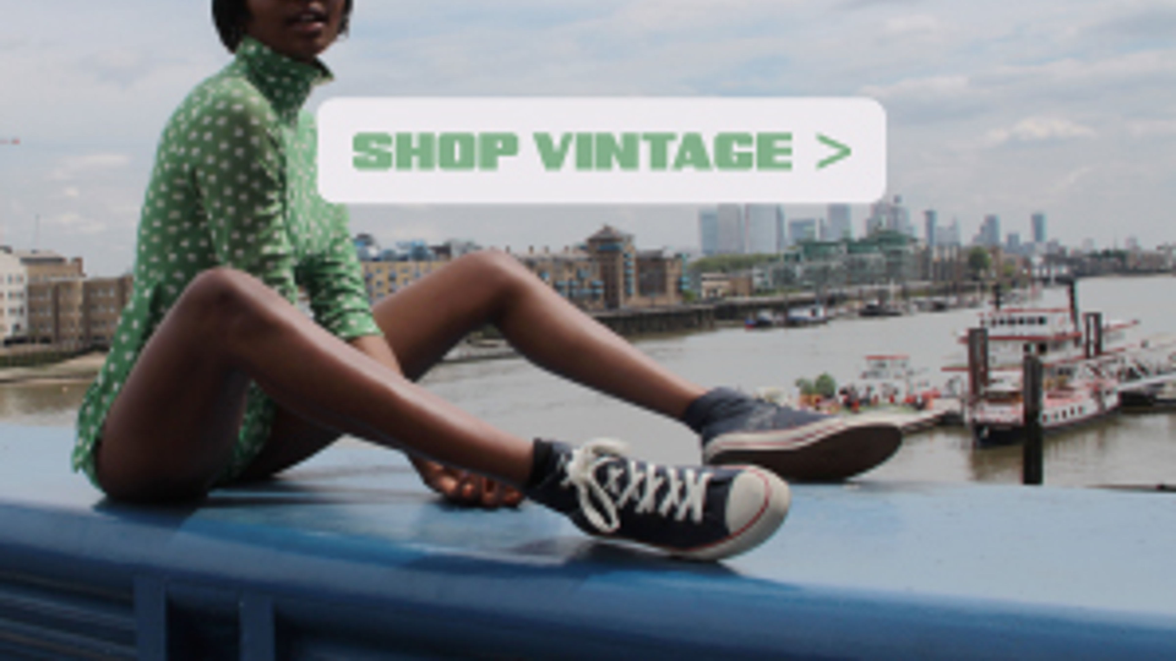 On the seaside, a girl in chic outfits sits, with the words 'Shop Vintage' nearby.