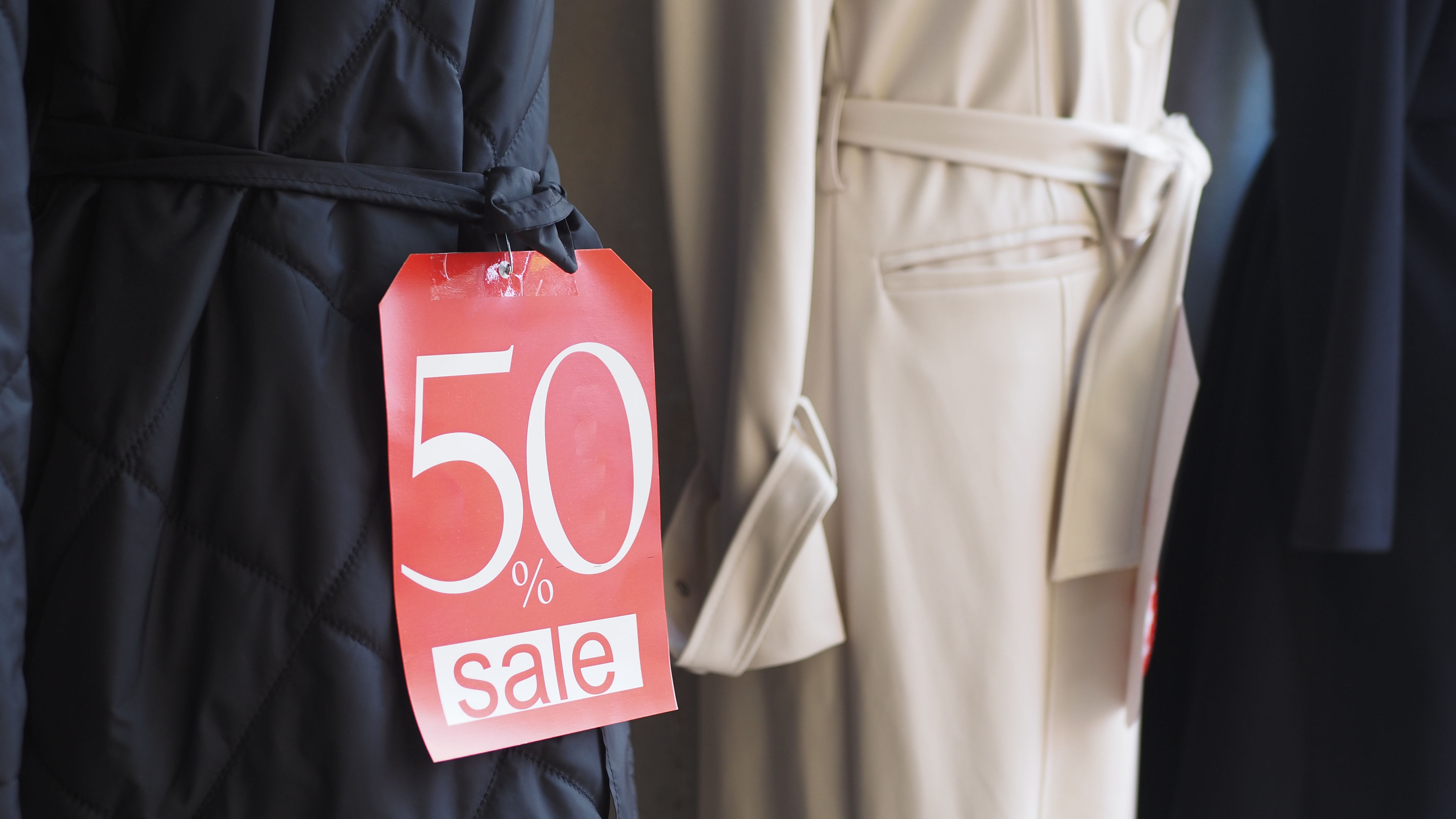 A red tag with "50% sale" written on it, pinned to a black quilted coat 