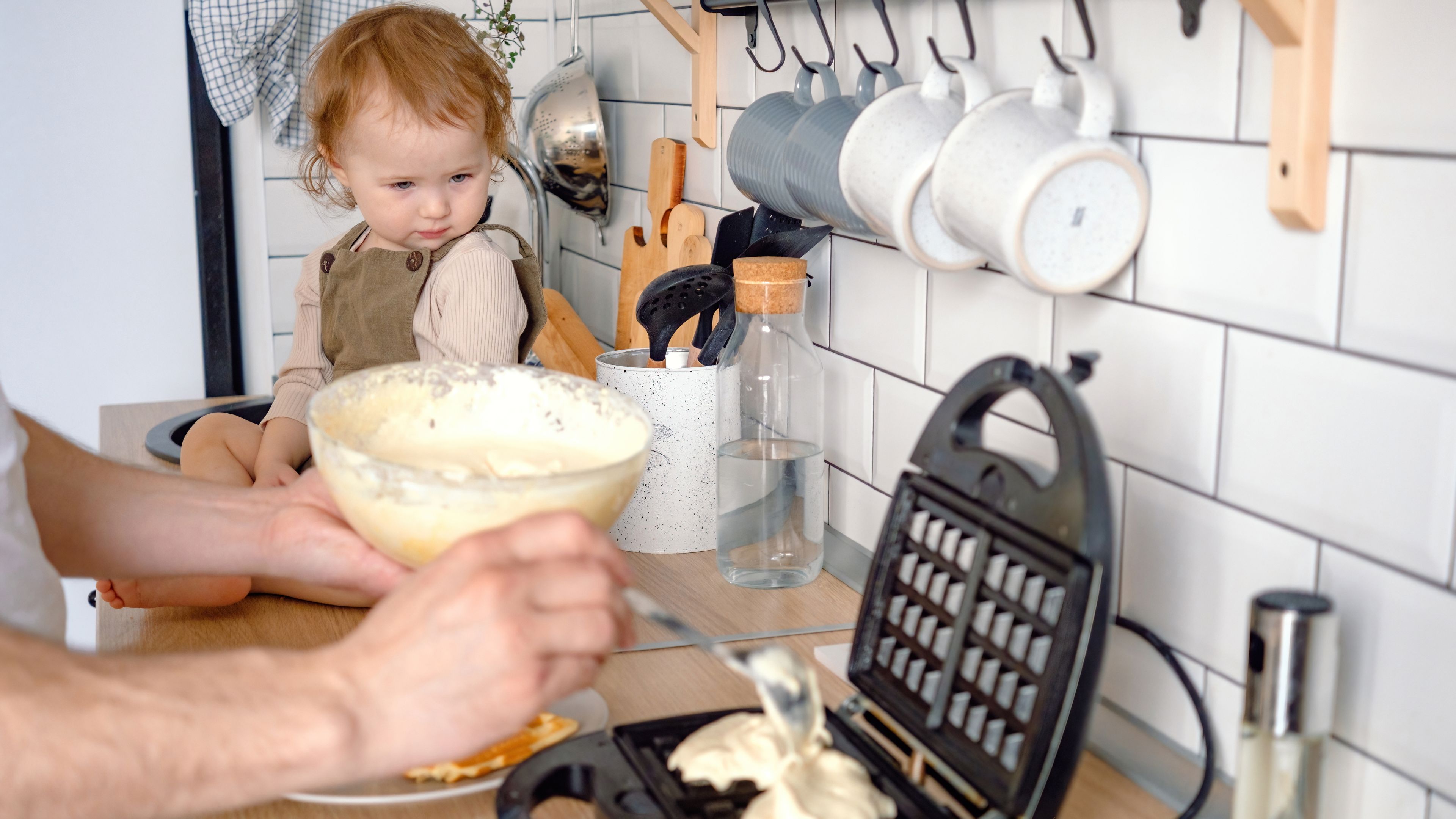 A hungry baby looking at a waffle maker 