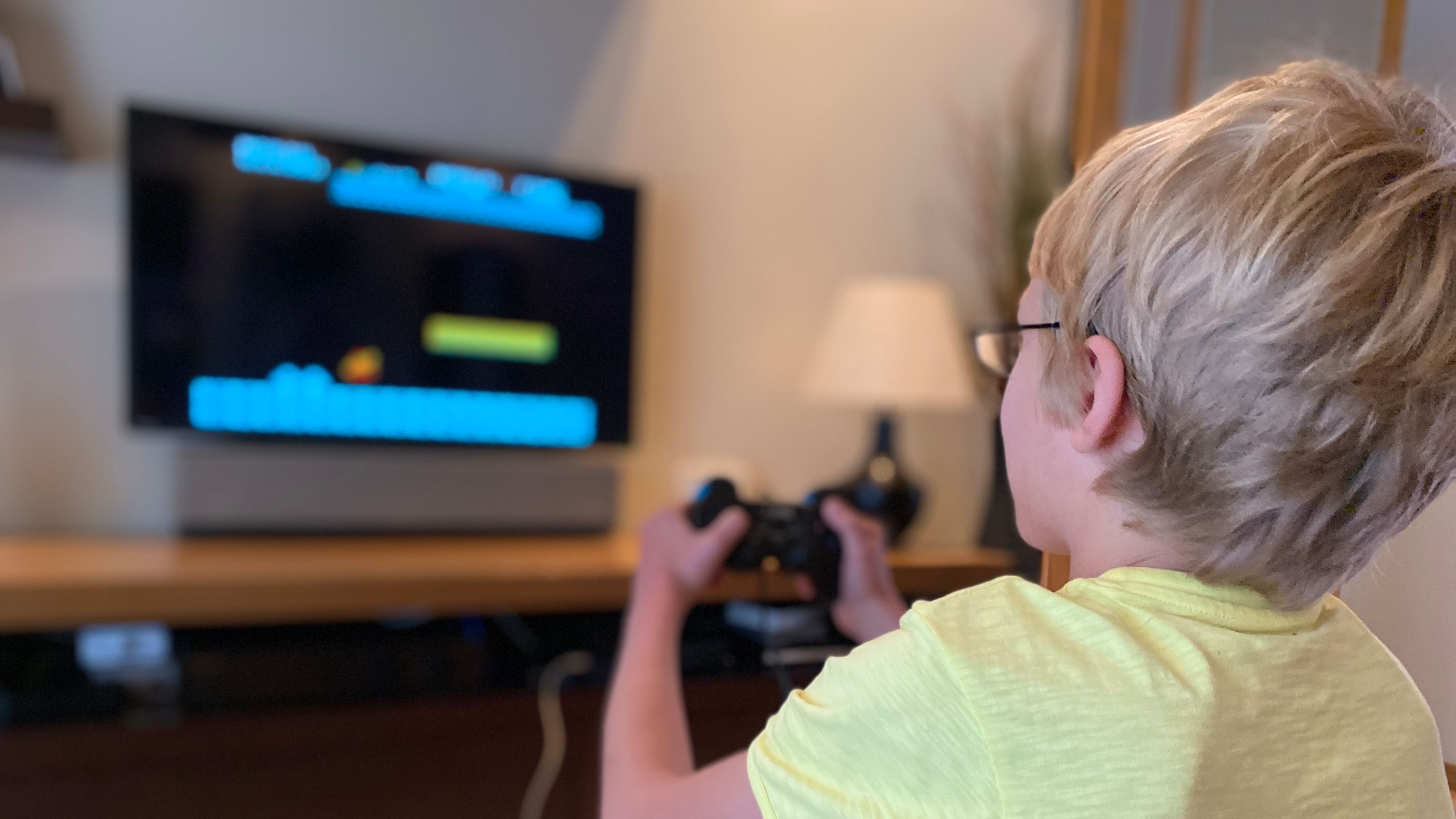 A boy relaxes at home, deeply focused on playing his favorite video game with a console in hand. 