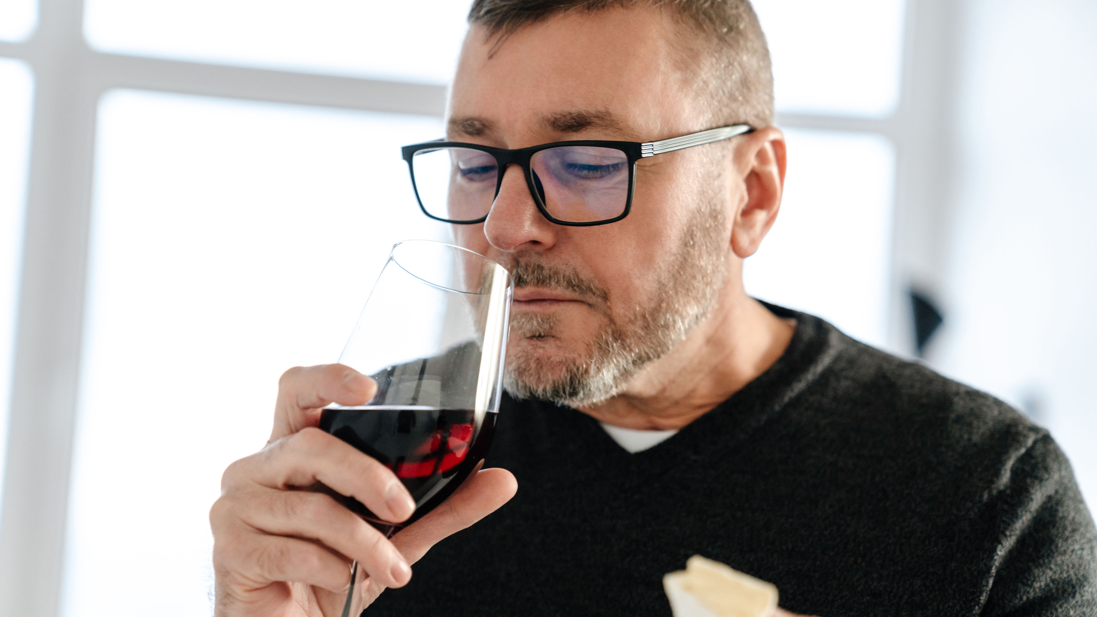 A middle-aged man is holding a glass of red wine 