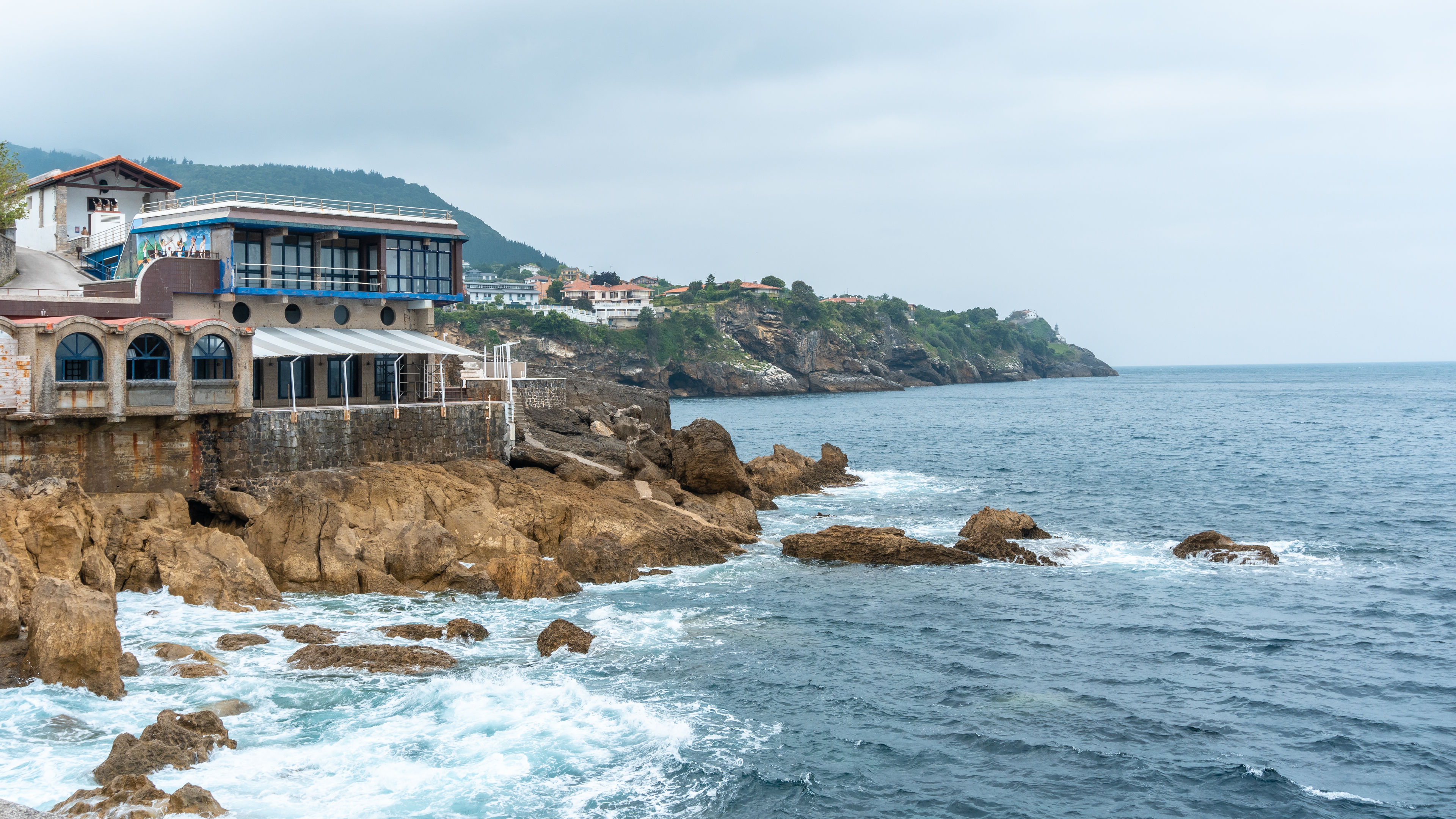 A scenic coastal town with houses and a restaurant.  