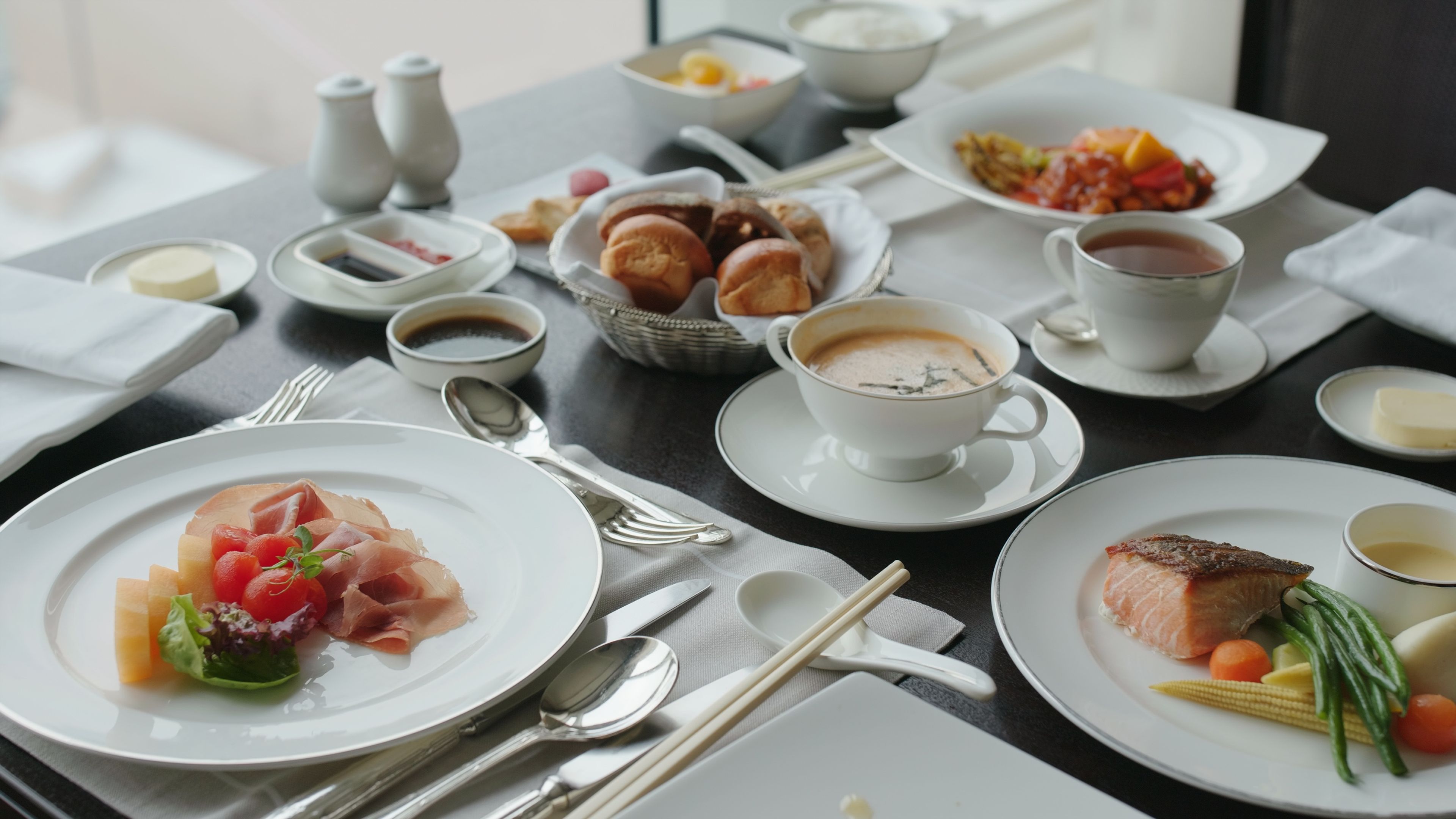 A beautifully arranged dining table featuring a variety of dishes, including bread, soup, fresh fruits, and coffee 