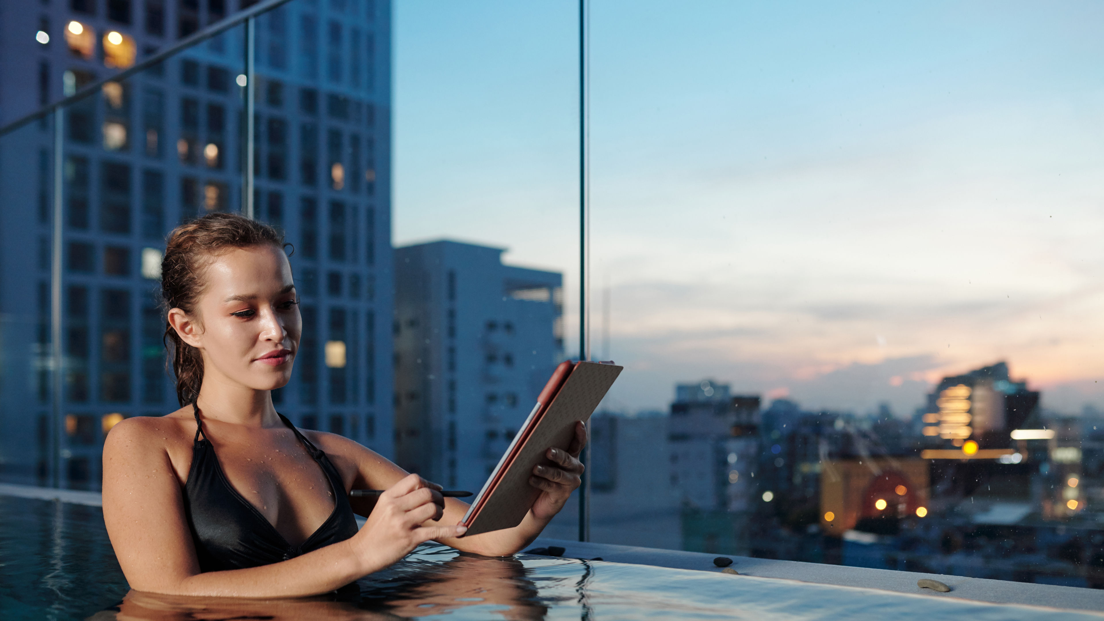  A woman in a pool looking at a tab 