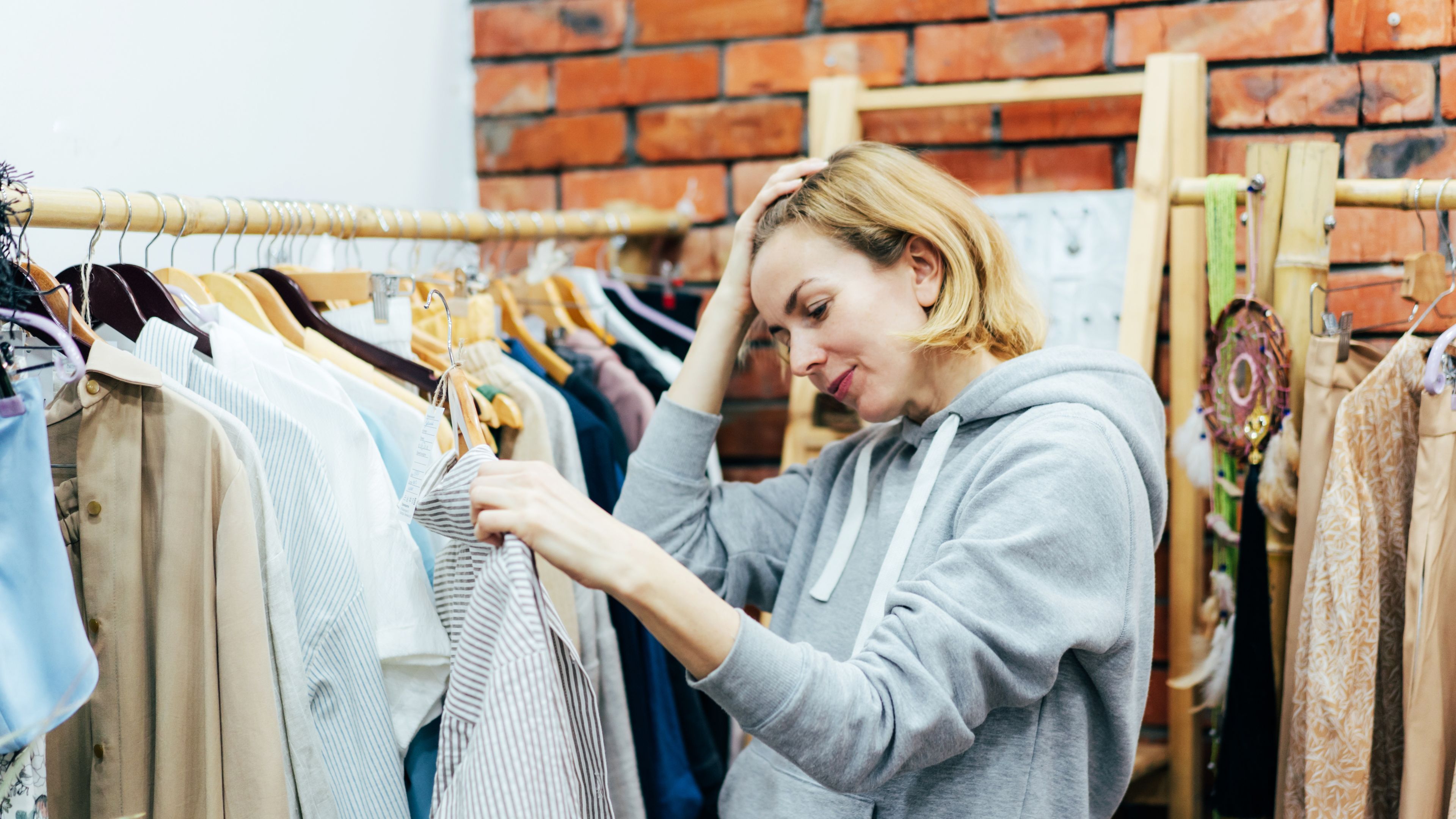 A happy woman selecting dresses in a shop 