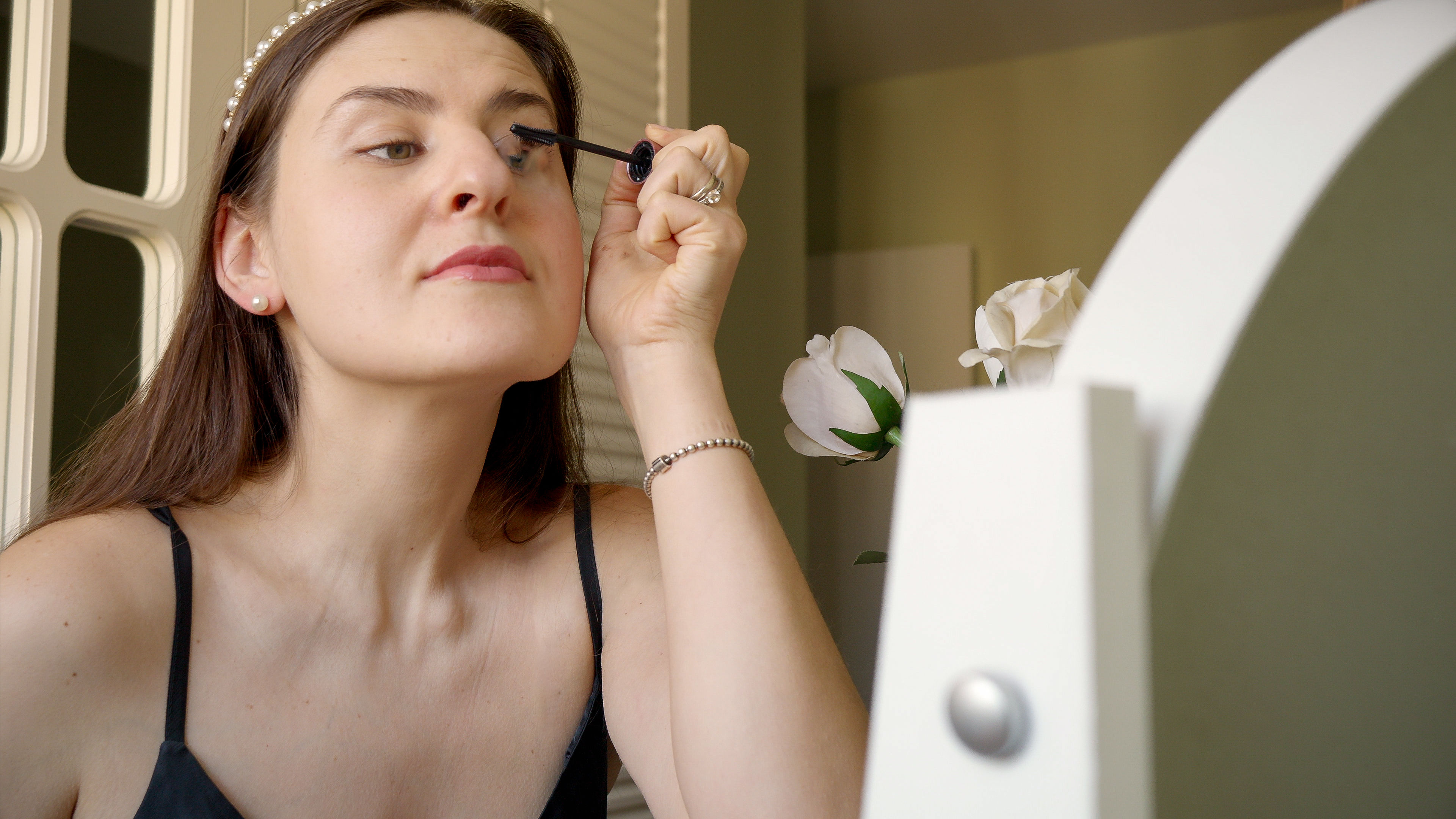 A young woman putting eyeliner by looking at a mirror