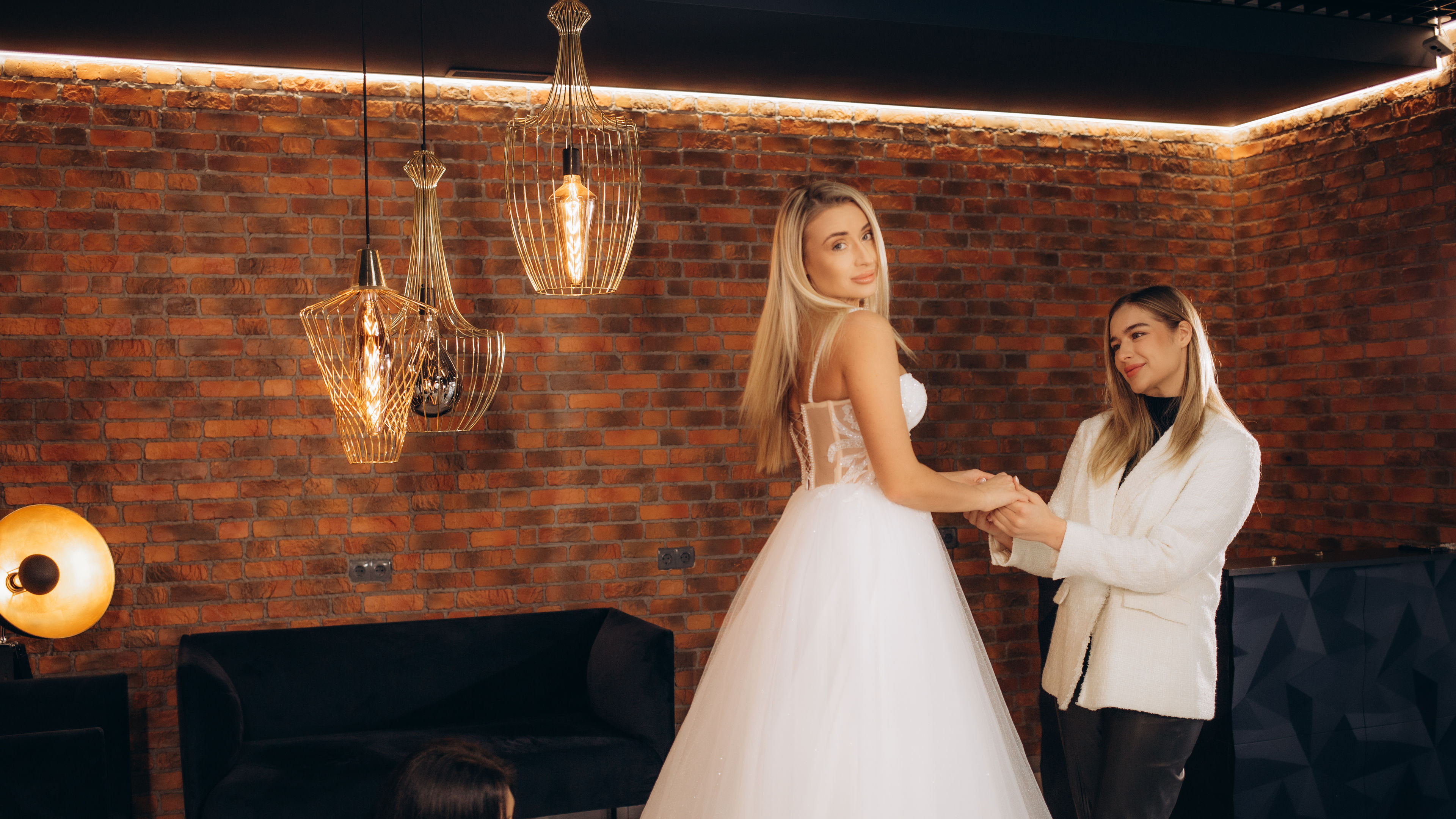 A bride stands gracefully in a bridal store, wearing a gown while discussing the fit with consultants 