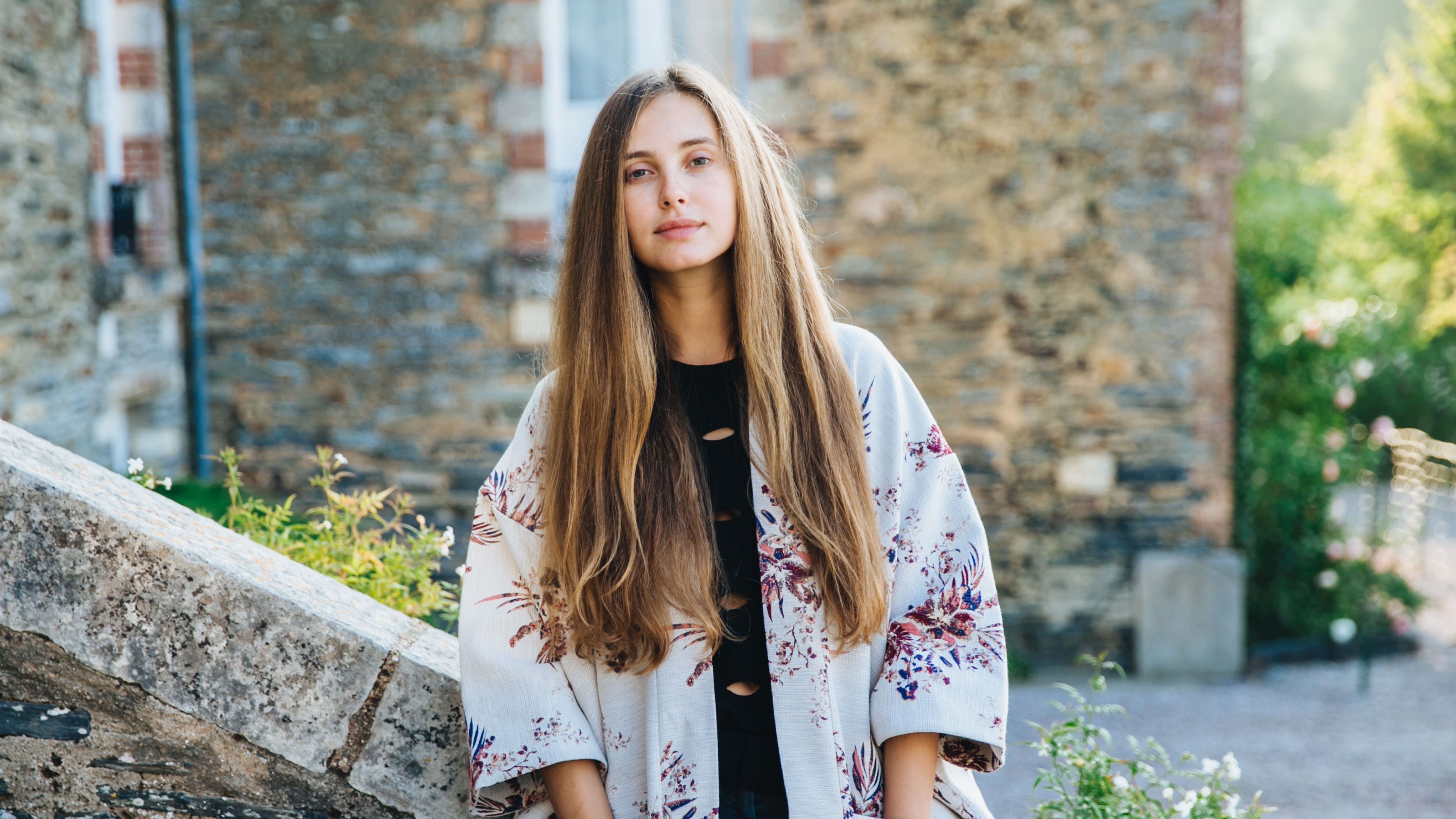 Confident pleasant looking young female poses against ancient bilduings as goes sightseeing in old town, wears fashionable clothes, poses outdoors.   