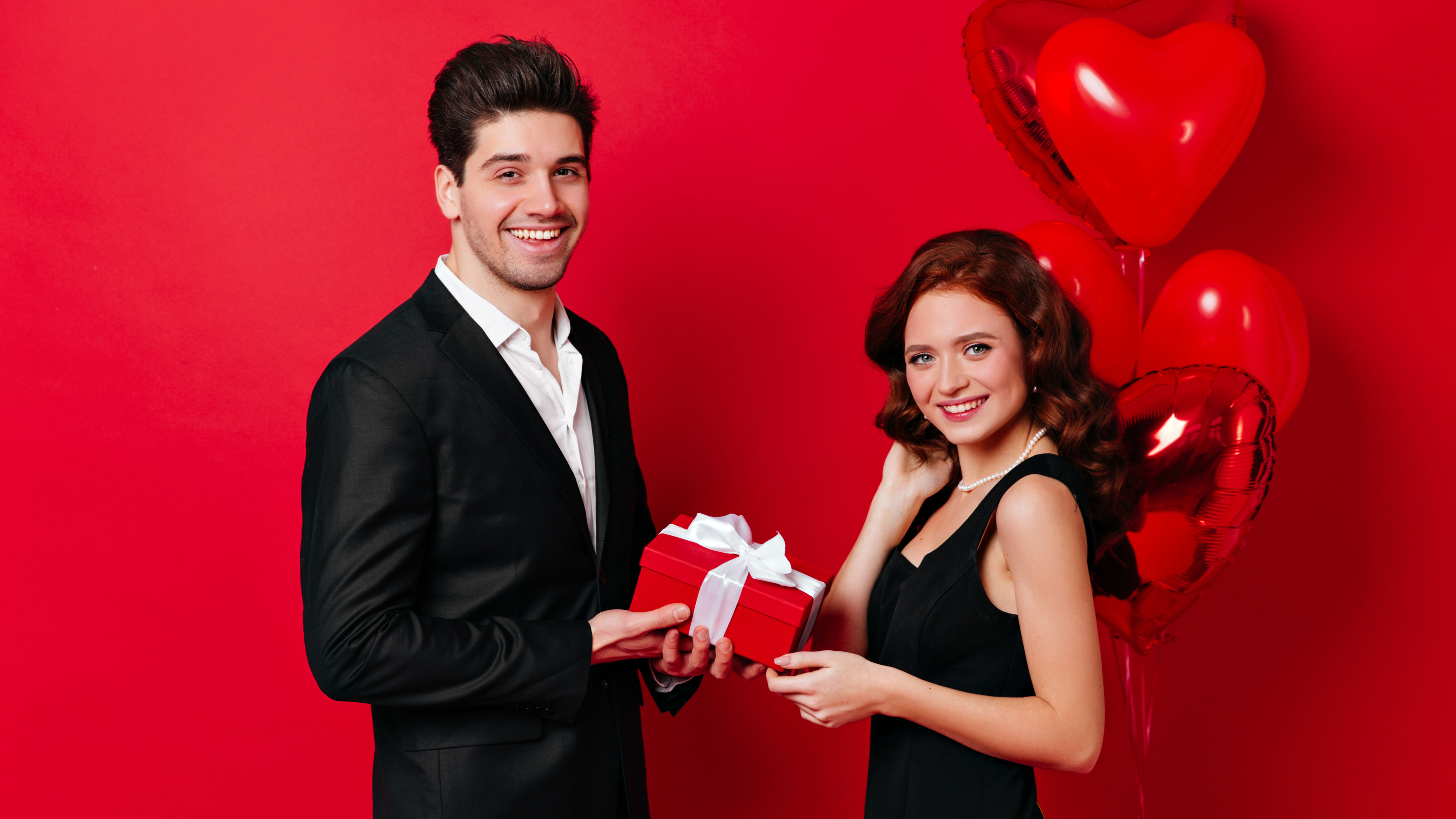 A smiling couple posing happily with balloons for Valentine’s Day. 