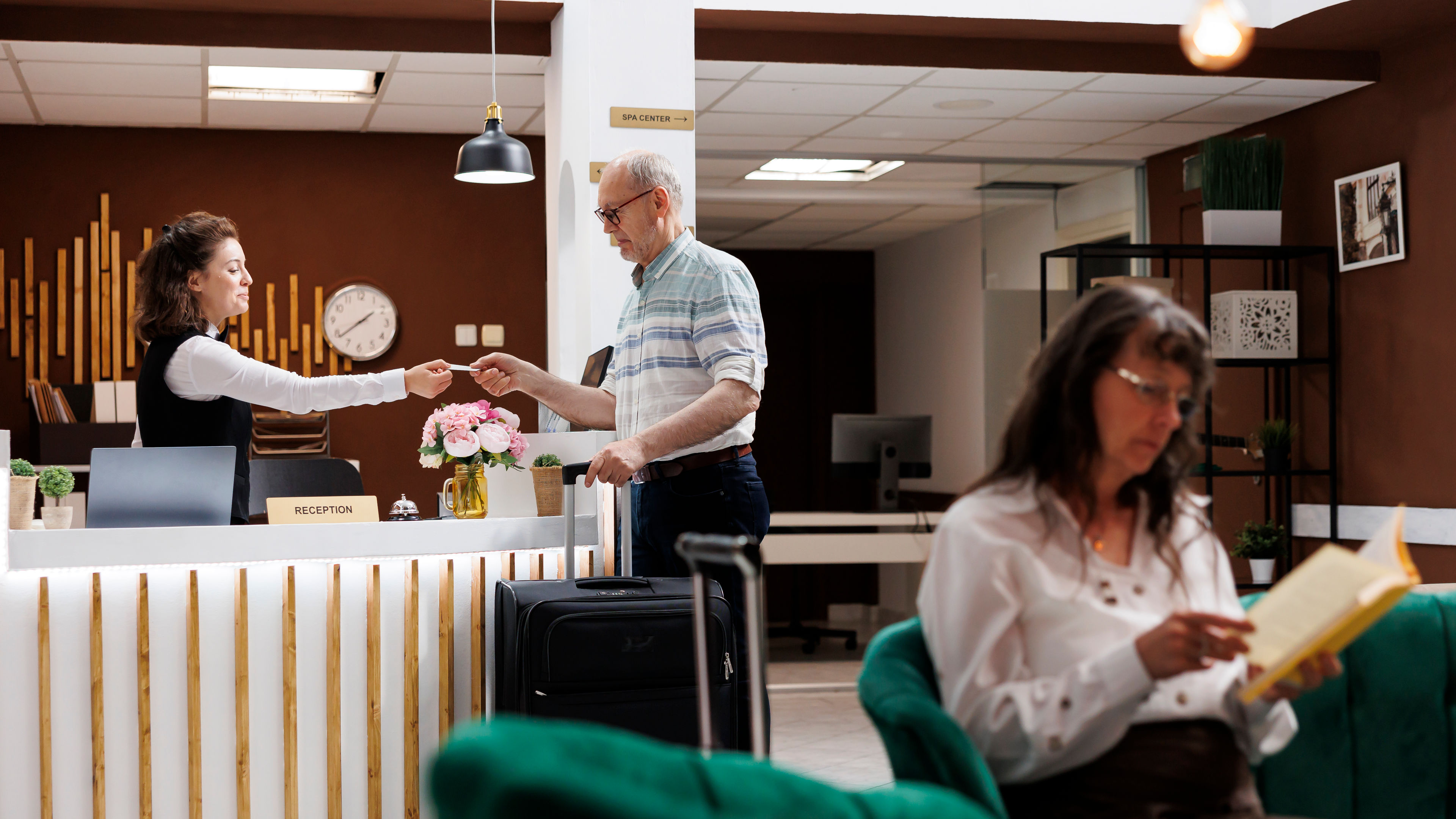 Elderly traveller obtains hotel key card. 