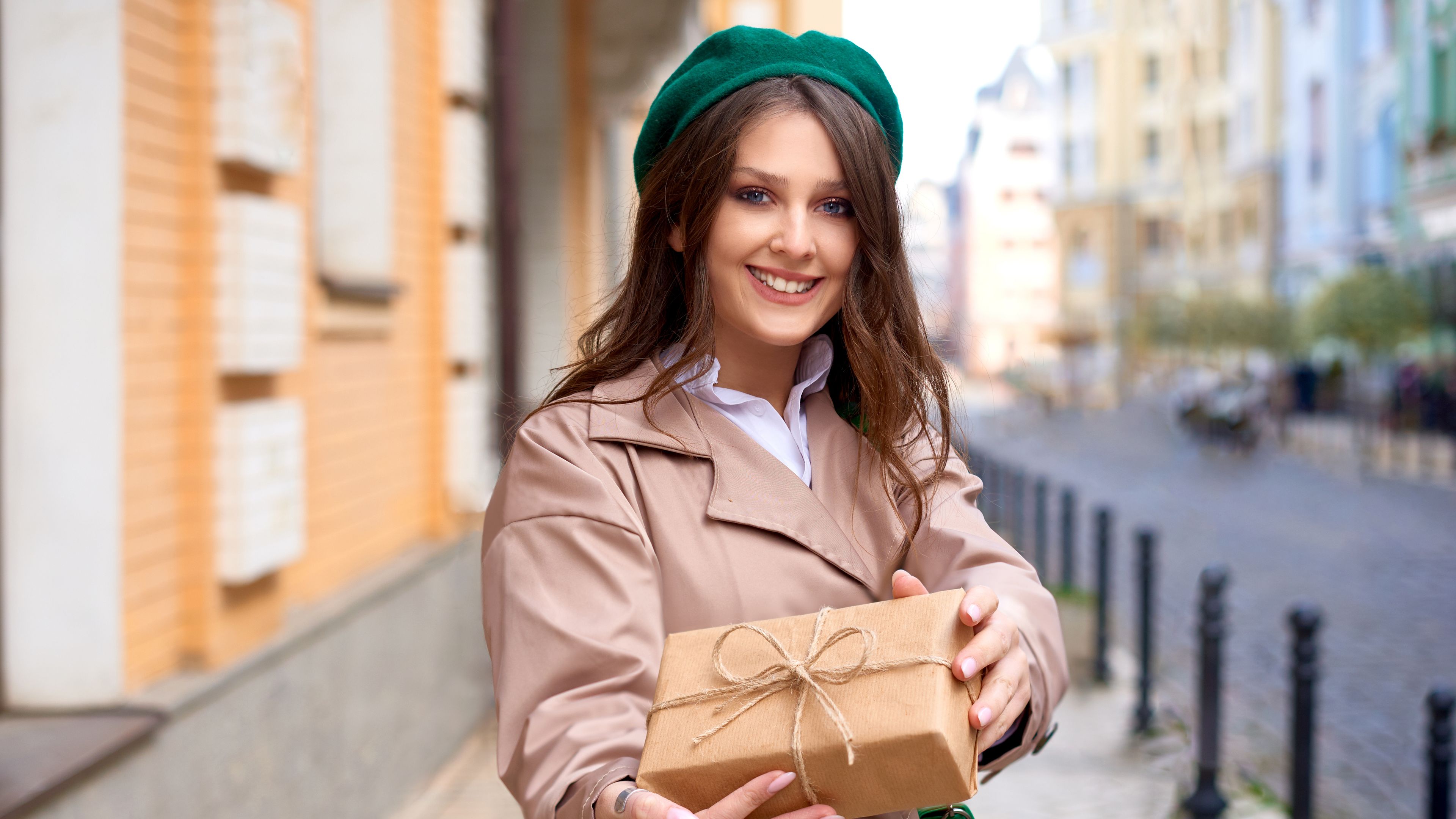 An elegant and attractive woman gracefully holding and presenting a beautifully wrapped gift. 