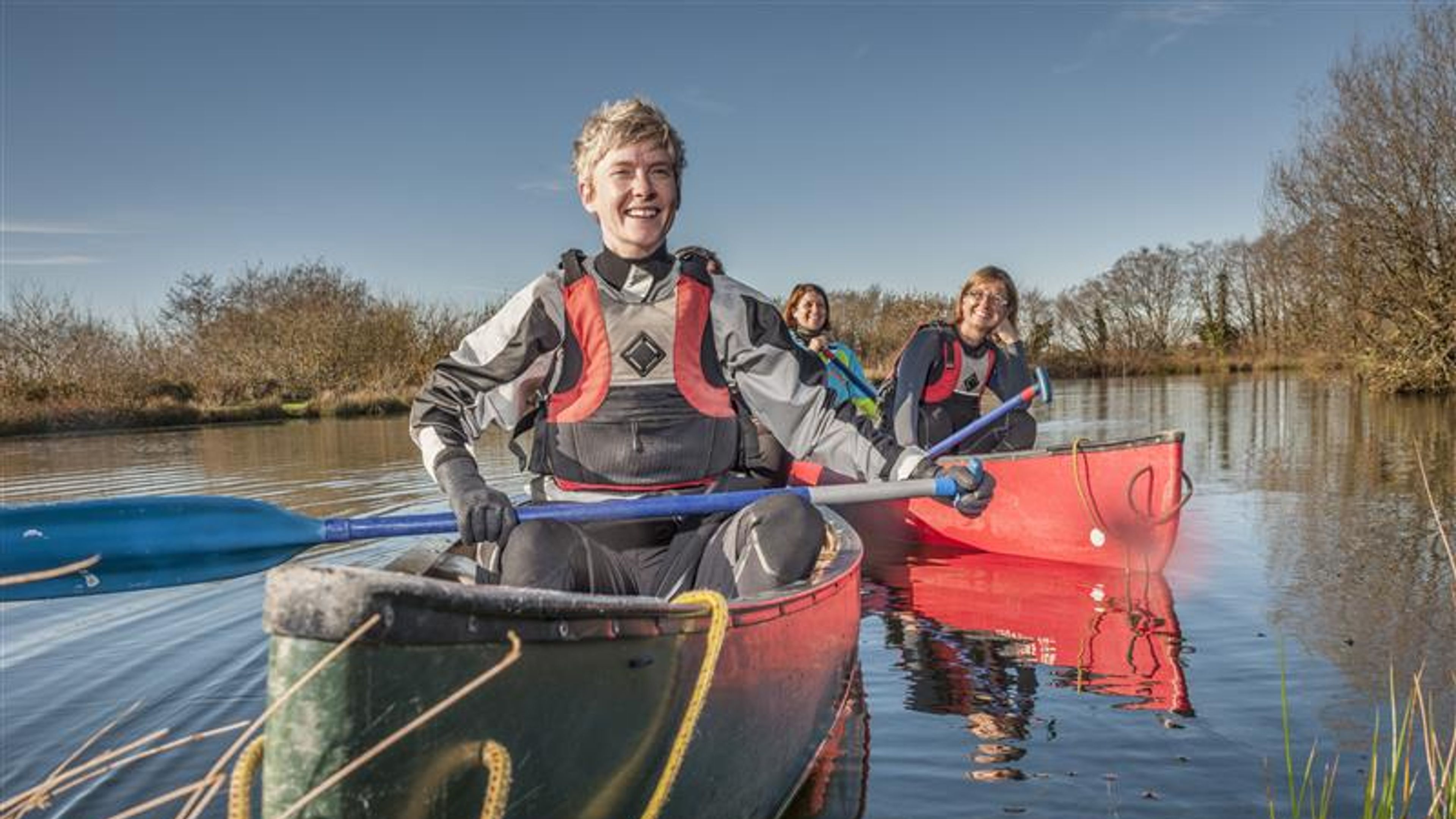 Friends enjoying a sunny day kayaking on a serene lake. 