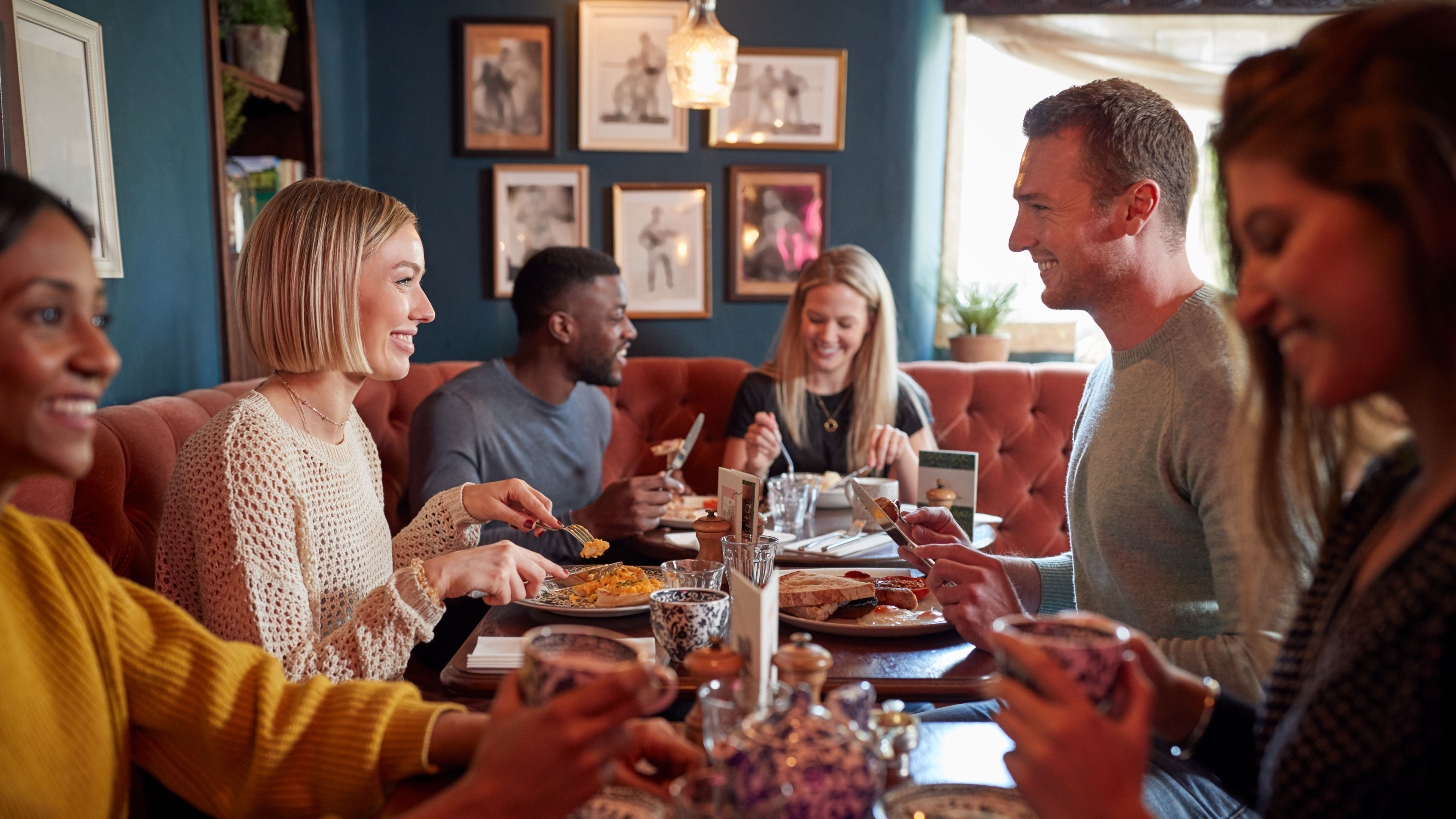 Group Of People Eating In Restaurant Of Busy Traditional English Pub 