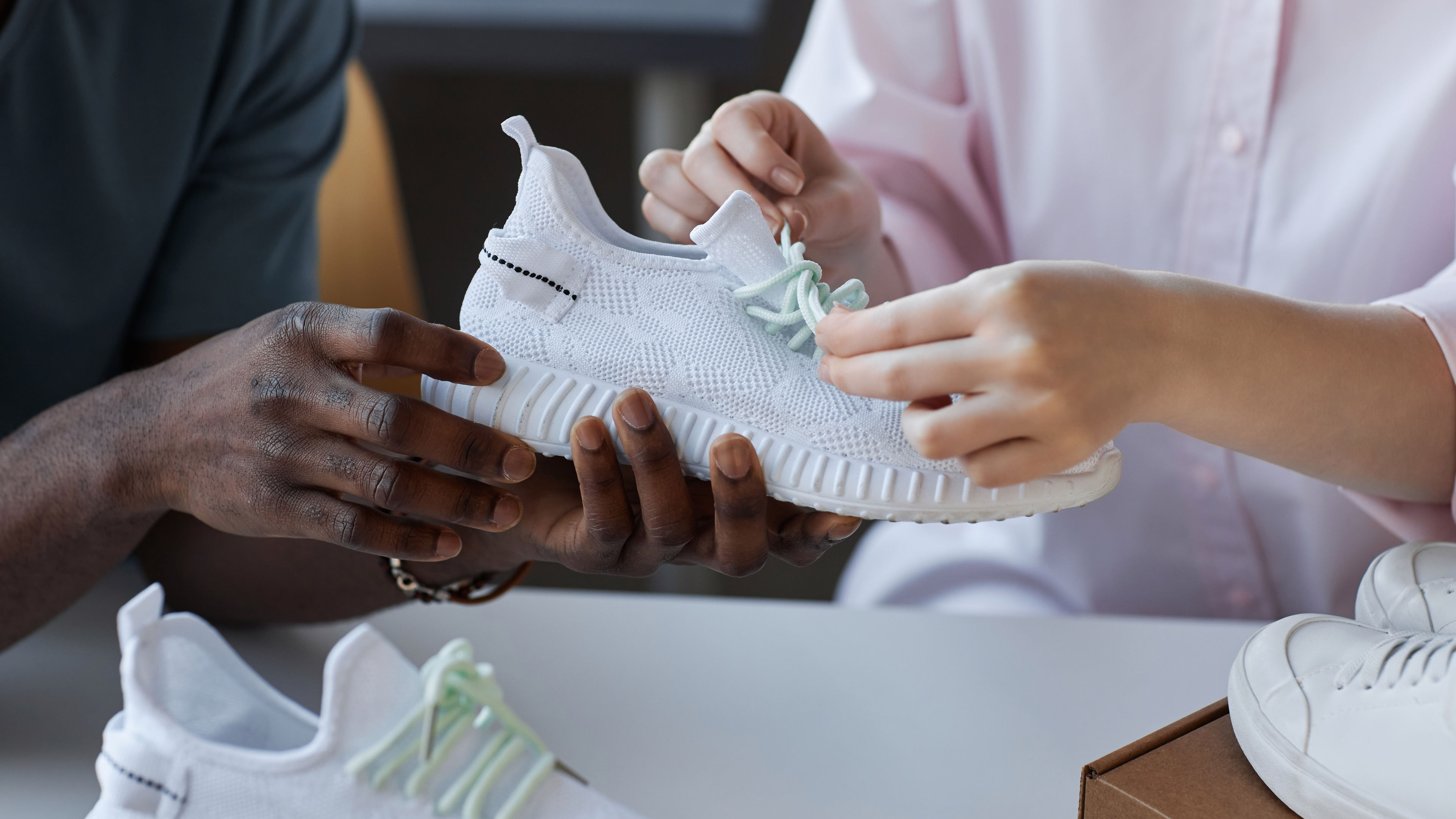 Hands of young intercultural couple unpacking parcel with new sneakers 