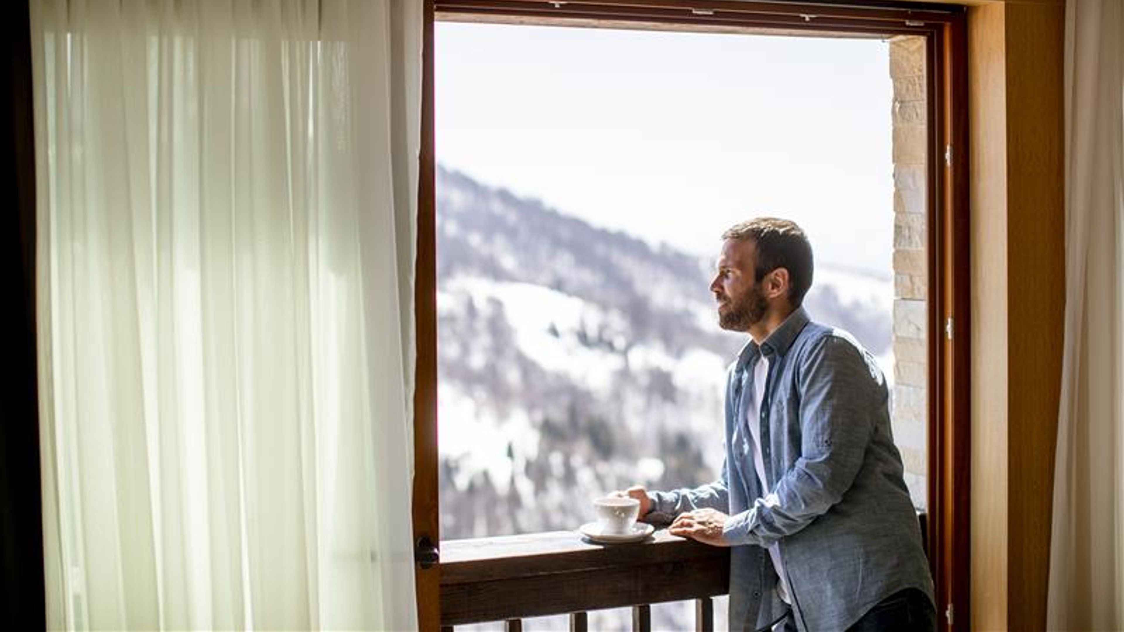 Handsome young man with cup of hot tea at the winter window 