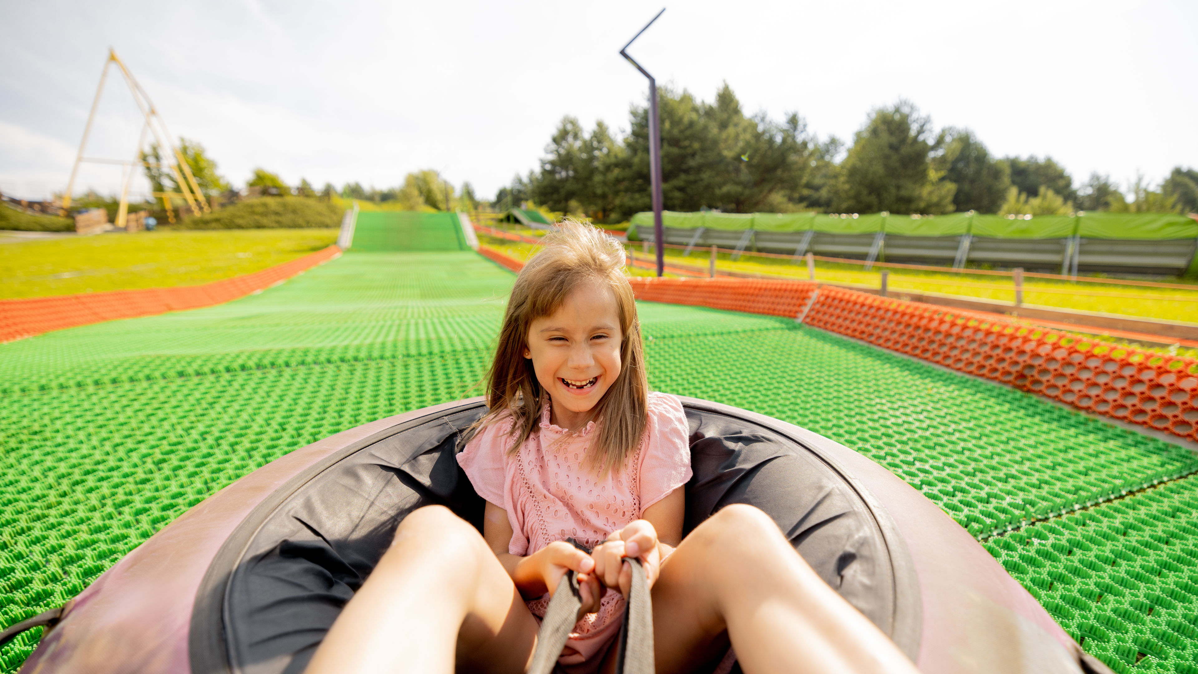 Happy girl descends in inflatable sledding tube at amusement park 