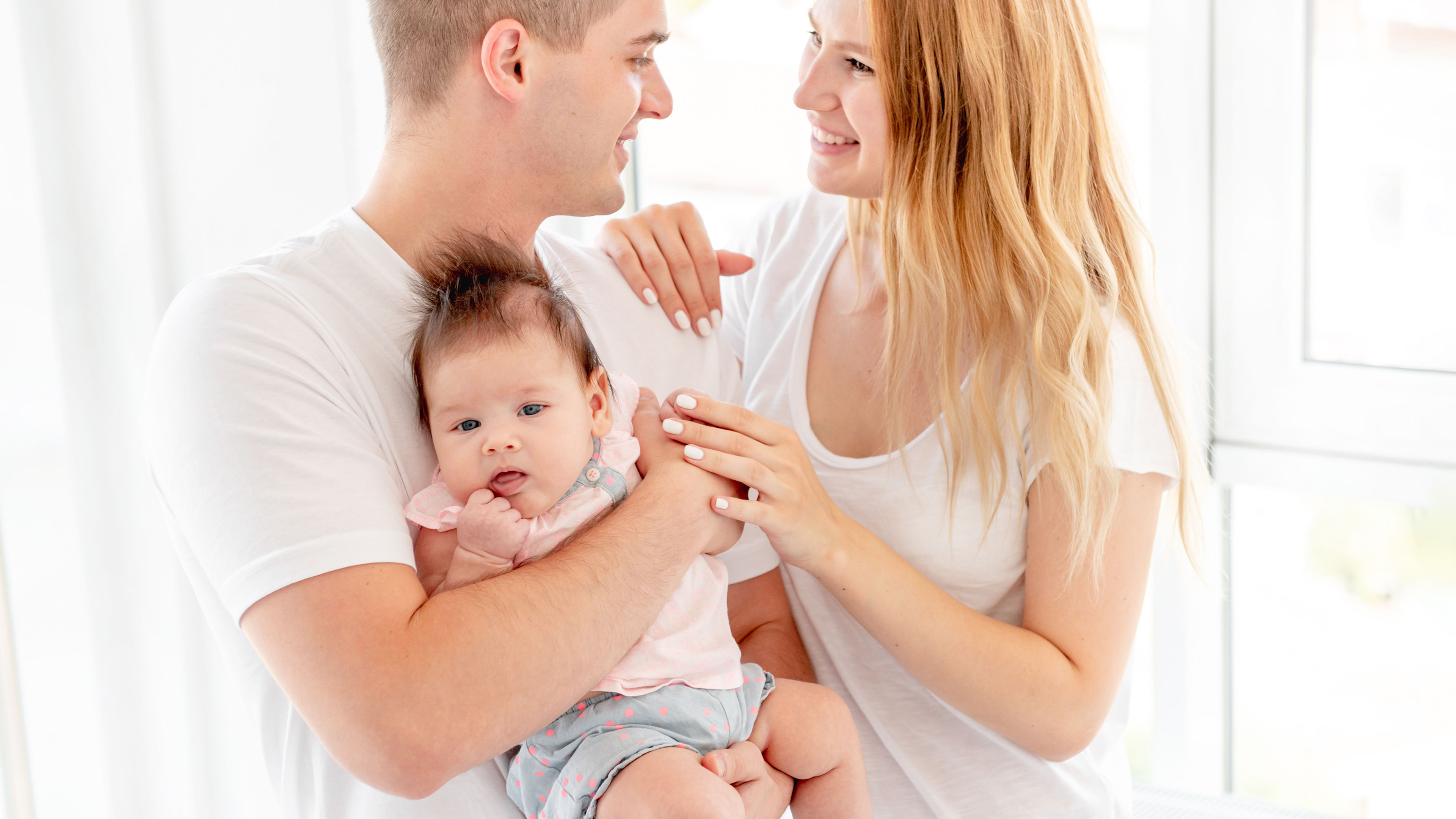 Happy parents holding a tiny baby 