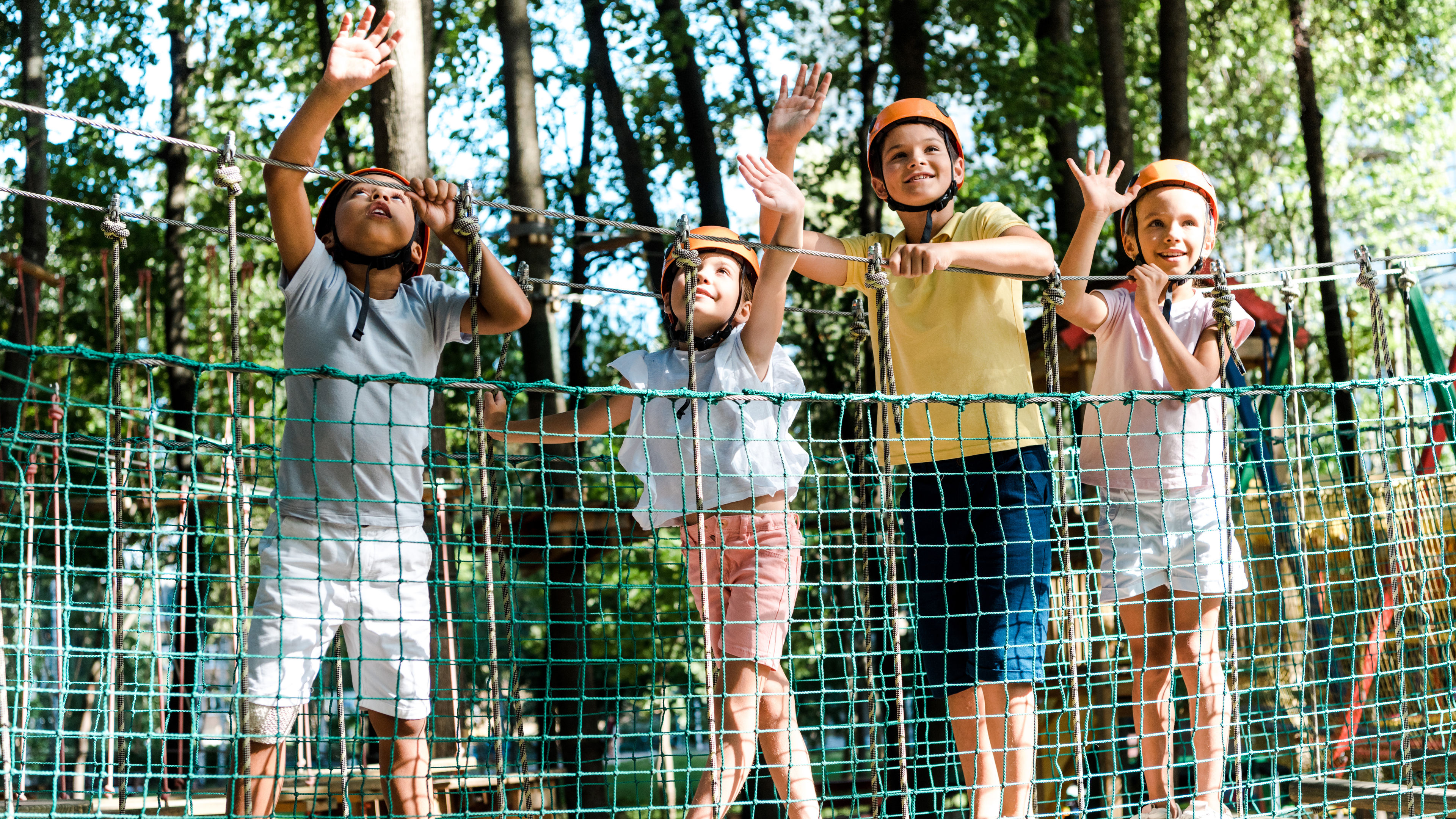 Kids in helmets enjoy a rope bridge activity 