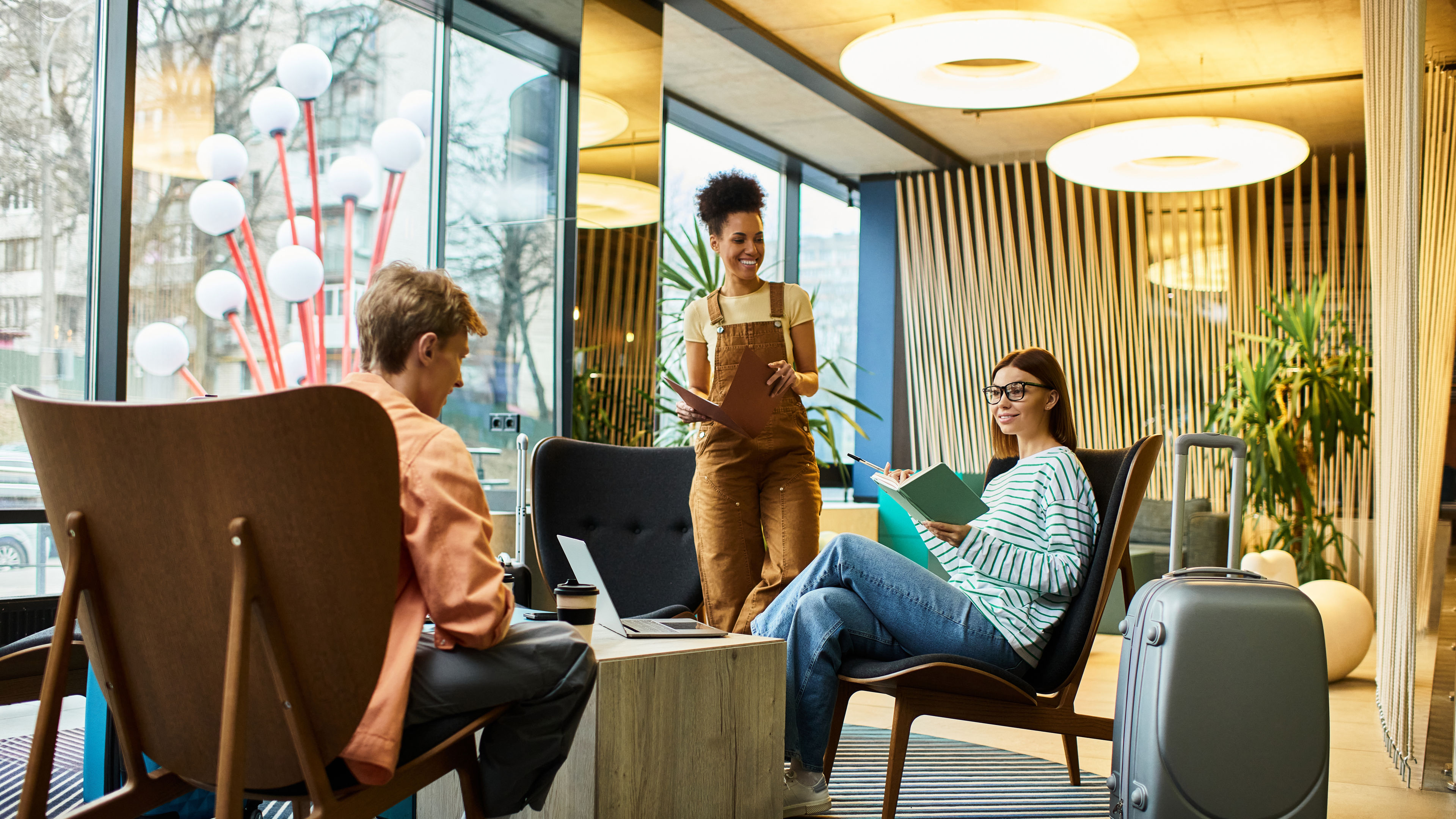 Three colleagues engage in discussions while relaxing in the modern hotel lounge area. 