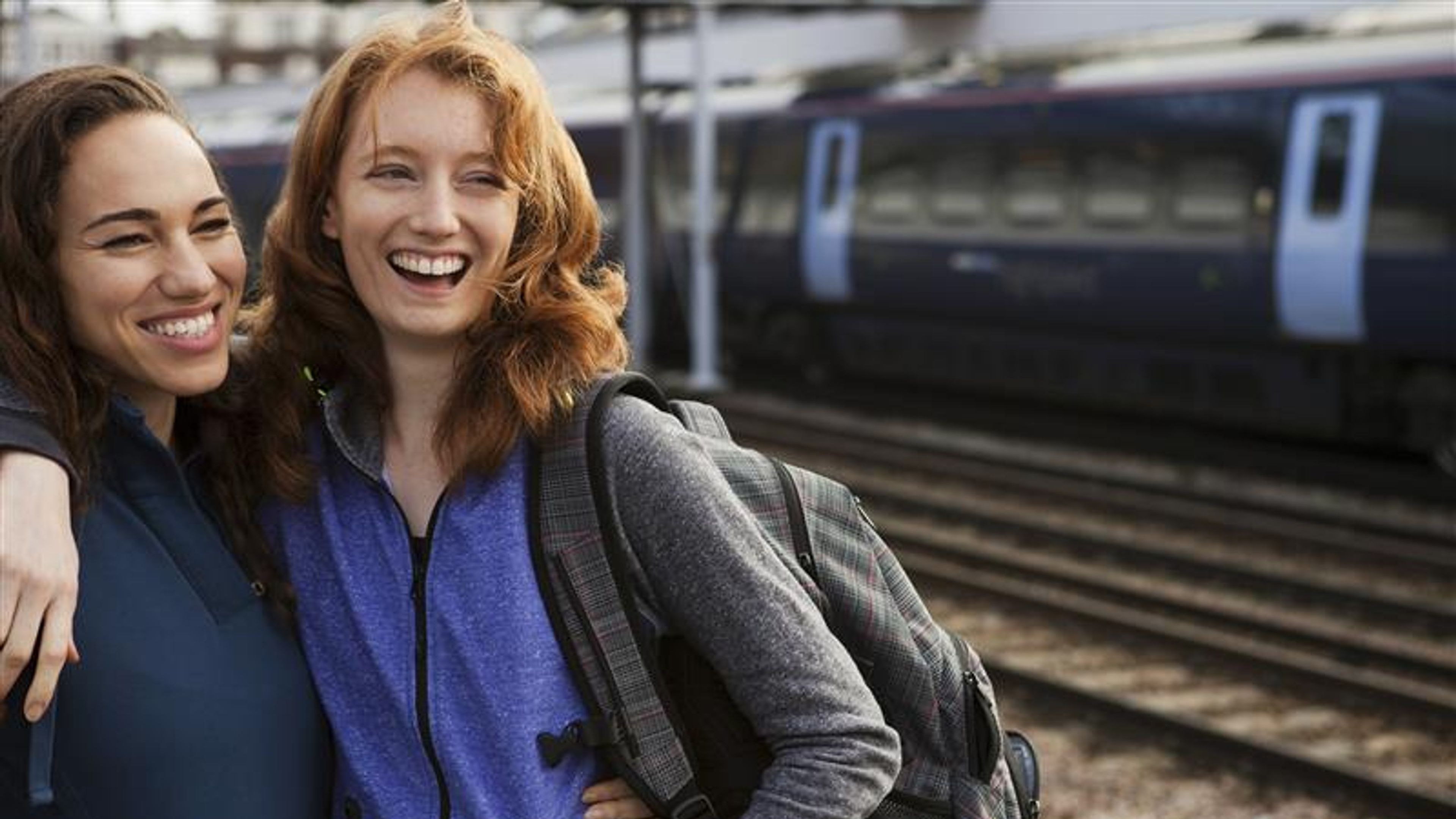 Two friends sharing a joyful moment at the train station. 