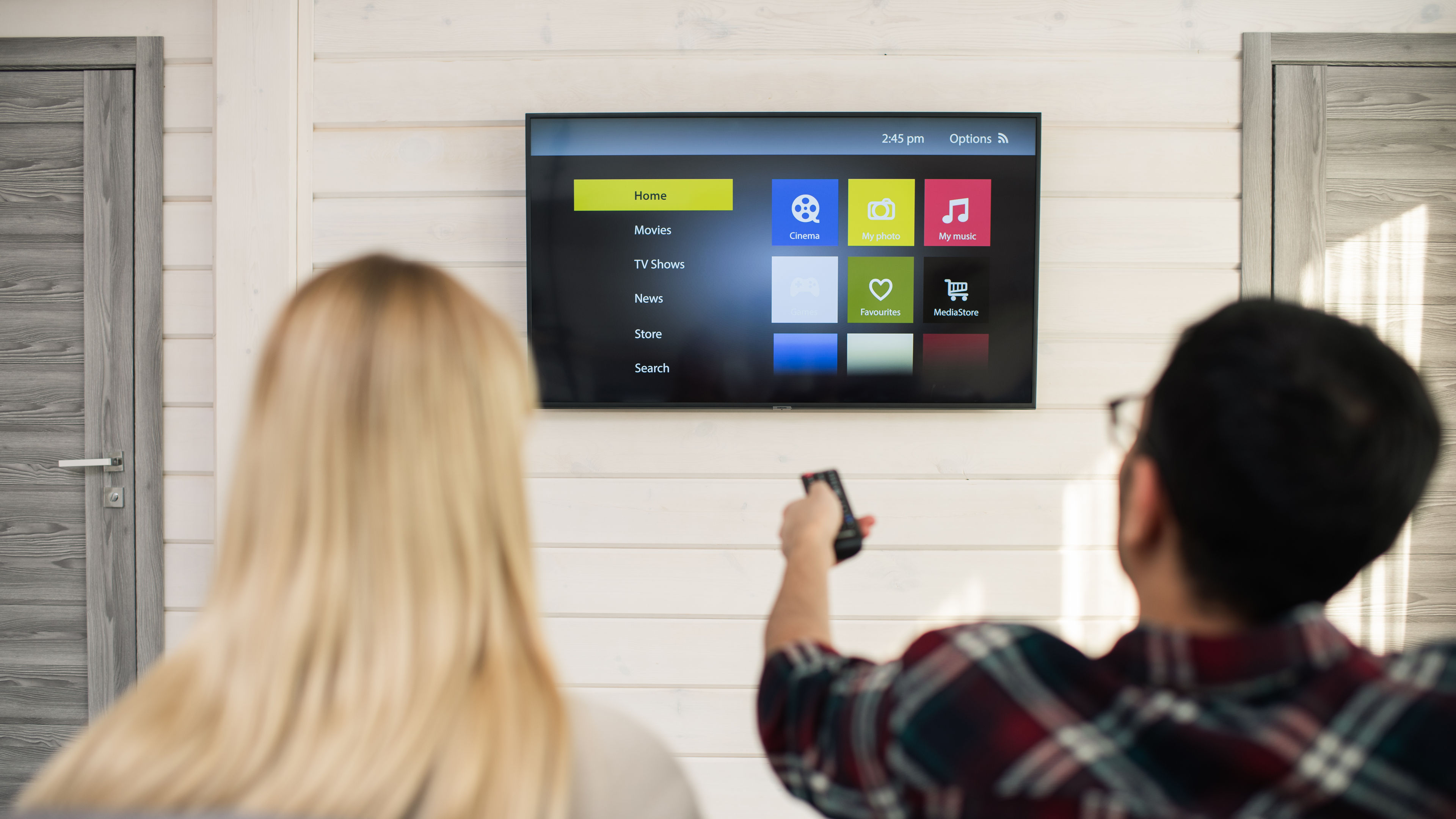 Young man choosing something to watch while sitting in front of tv set 